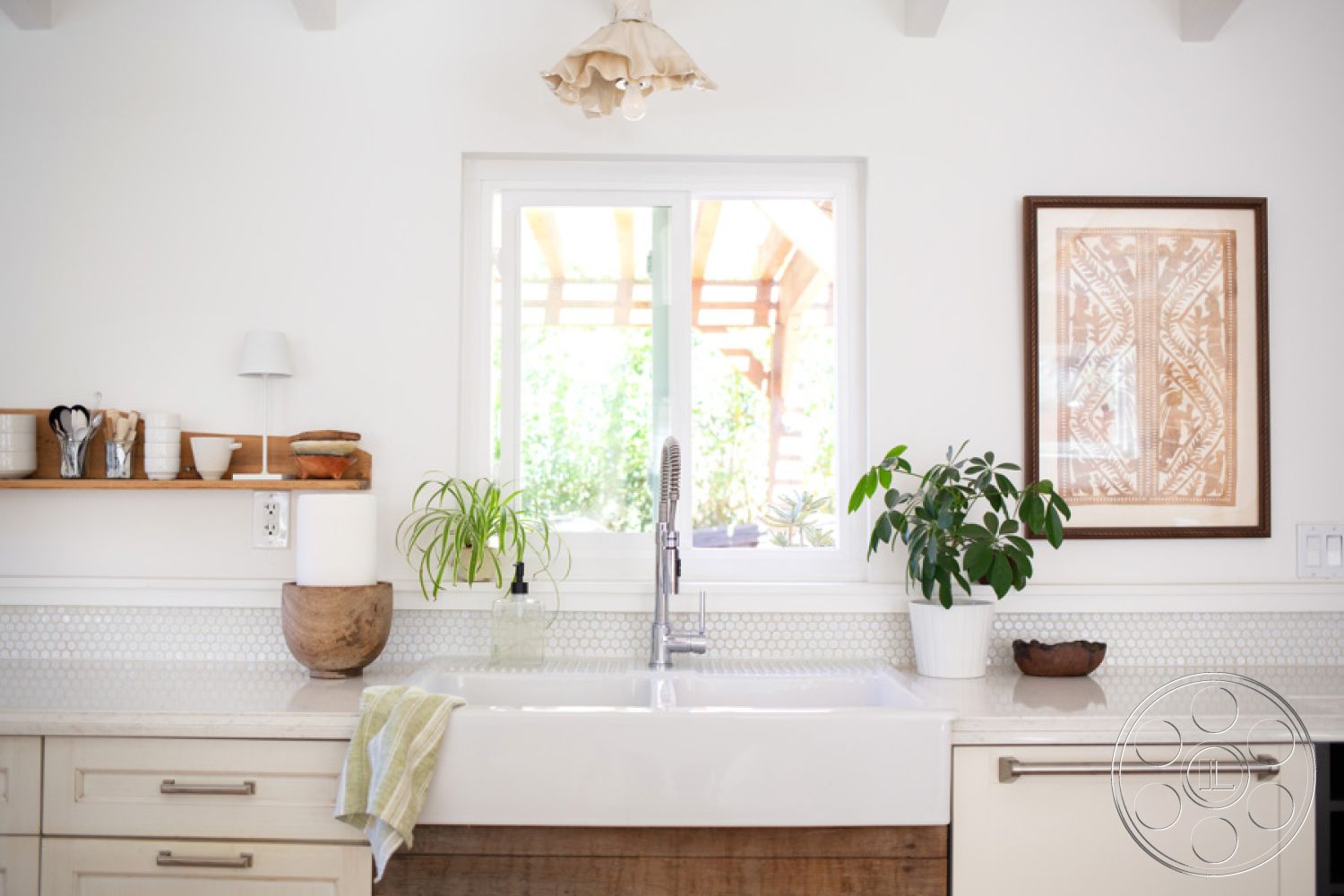 Ranch 33 - quartz countertop, natural wood accents, light wood cabinetry, decorative wall art, farmhouse sink, green potted plant, modern light fixture, minimalist kitchen design, stainless steel kitchen faucet, white painted walls, wooden floating shelf, hexagonal tile kitchen backsplash, open window with natural light
