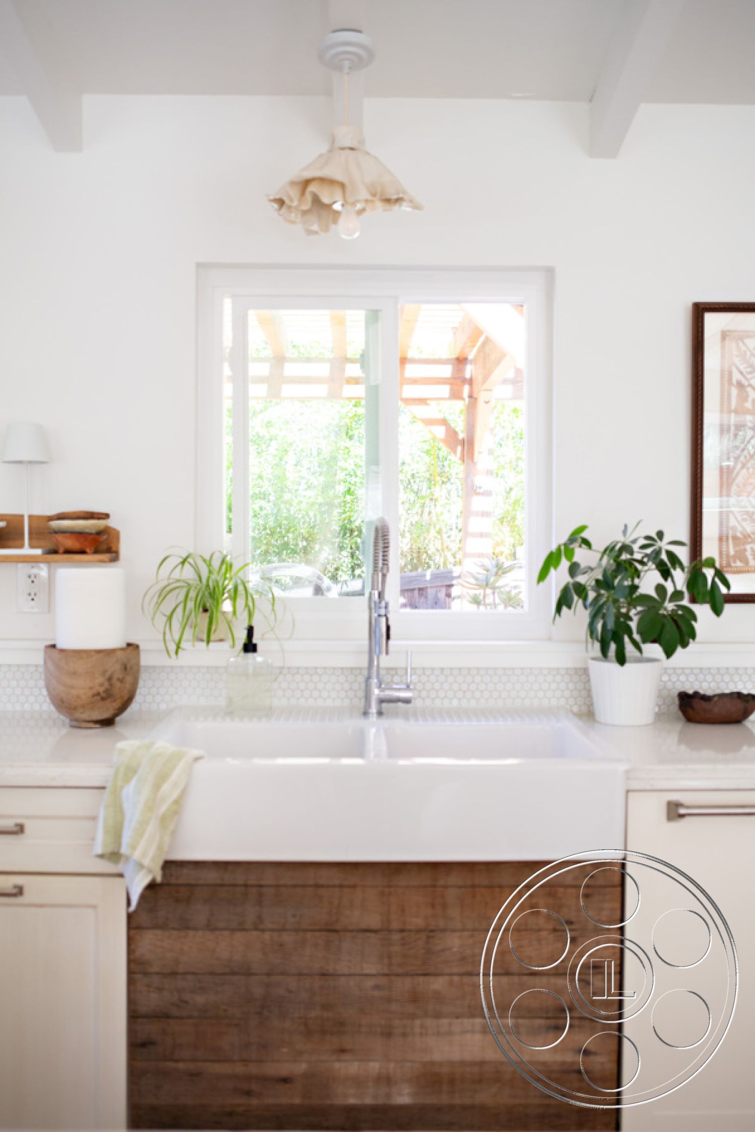 Ranch 33 - minimalist decor, green indoor plants, natural light from large windows, hexagonal tile backsplash, modern kitchen design, open kitchen layout, stainless steel kitchen faucet, clean lines and simplicity, wood beam ceiling details, warm wood textures, soft lighting fixture, white cabinetry with wood accents, apron-front farmhouse sink, textured wood cabinet doors, light-colored countertop, integrated kitchen storage