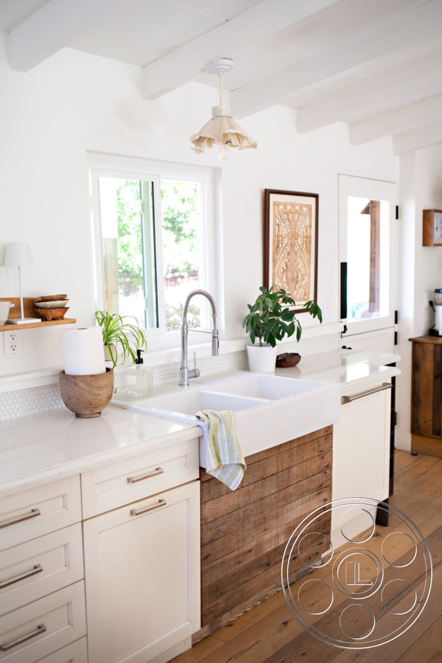 Ranch 33 - subway tile backsplash, modern pendant lighting, large windows for natural light, exposed wood ceiling beams, stainless steel kitchen faucet, open concept kitchen layout, interior kitchen with quartz countertop, hardwood floor in kitchen, elegant kitchen island, minimalist decor with potted plants, white painted cabinets, farmhouse sink with apron front, wood paneling base on cabinetry, rustic and contemporary design elements