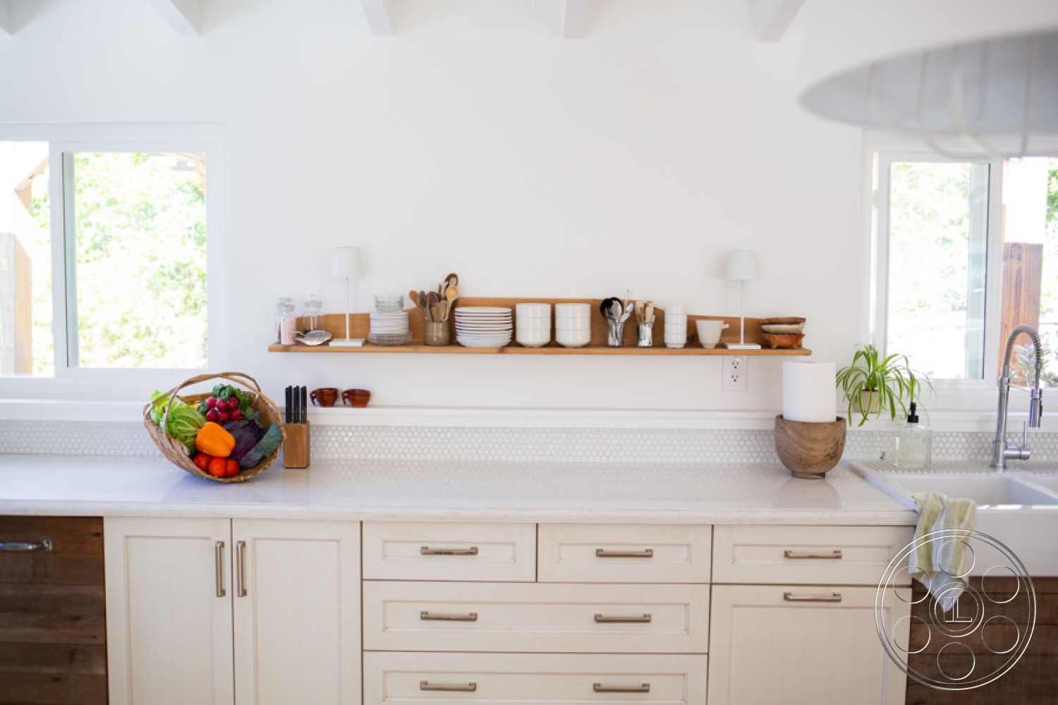 Ranch 33 - natural light from large windows, hexagonal tile backsplash, modern kitchen appliances, minimalist kitchen decor, hardwood flooring in kitchen area, interior kitchen with white painted walls, marble countertops with integrated sink, white cabinetry with brushed nickel handles, wood floating shelf with dishware, potted plant on countertop, open layout kitchen with dining area, exposed beam ceiling details