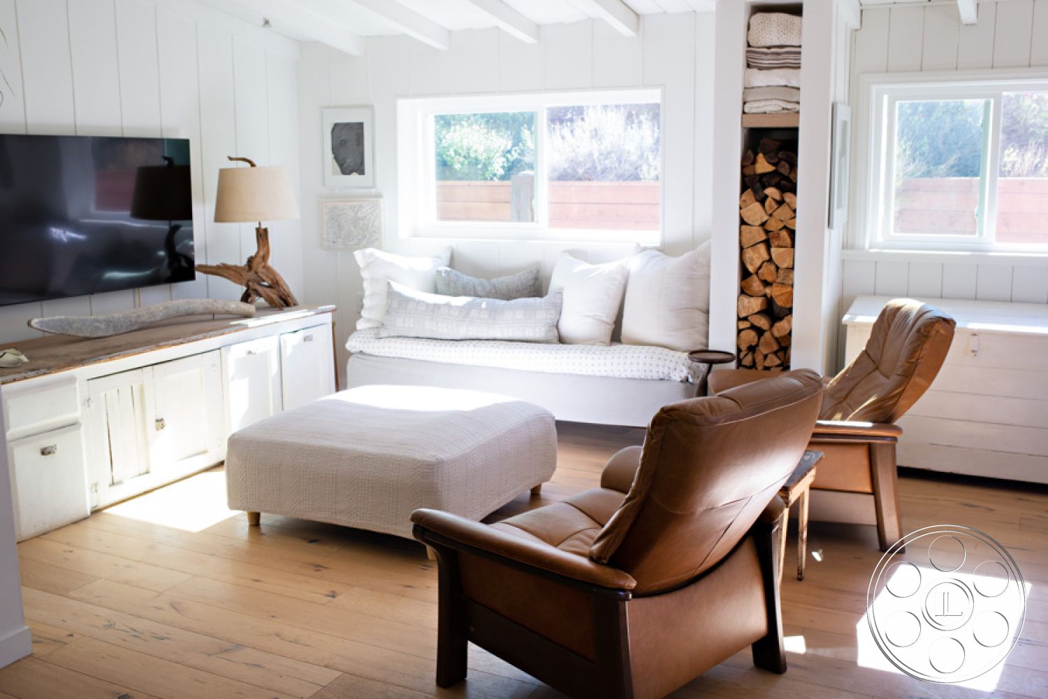 Ranch 33 - neutral color palette, firewood storage, white shiplap walls, minimalist coffee table, natural wood finish, cozy reading nook, modern light fixture, exposed wood ceiling beams, natural light through windows, rural farmhouse aesthetic, open concept interior, wooden plank flooring, contemporary home office, plush upholstery sofa, stone accent decor, stylish leather armchairs, modern television unit, serene indoor environment, suburban living room