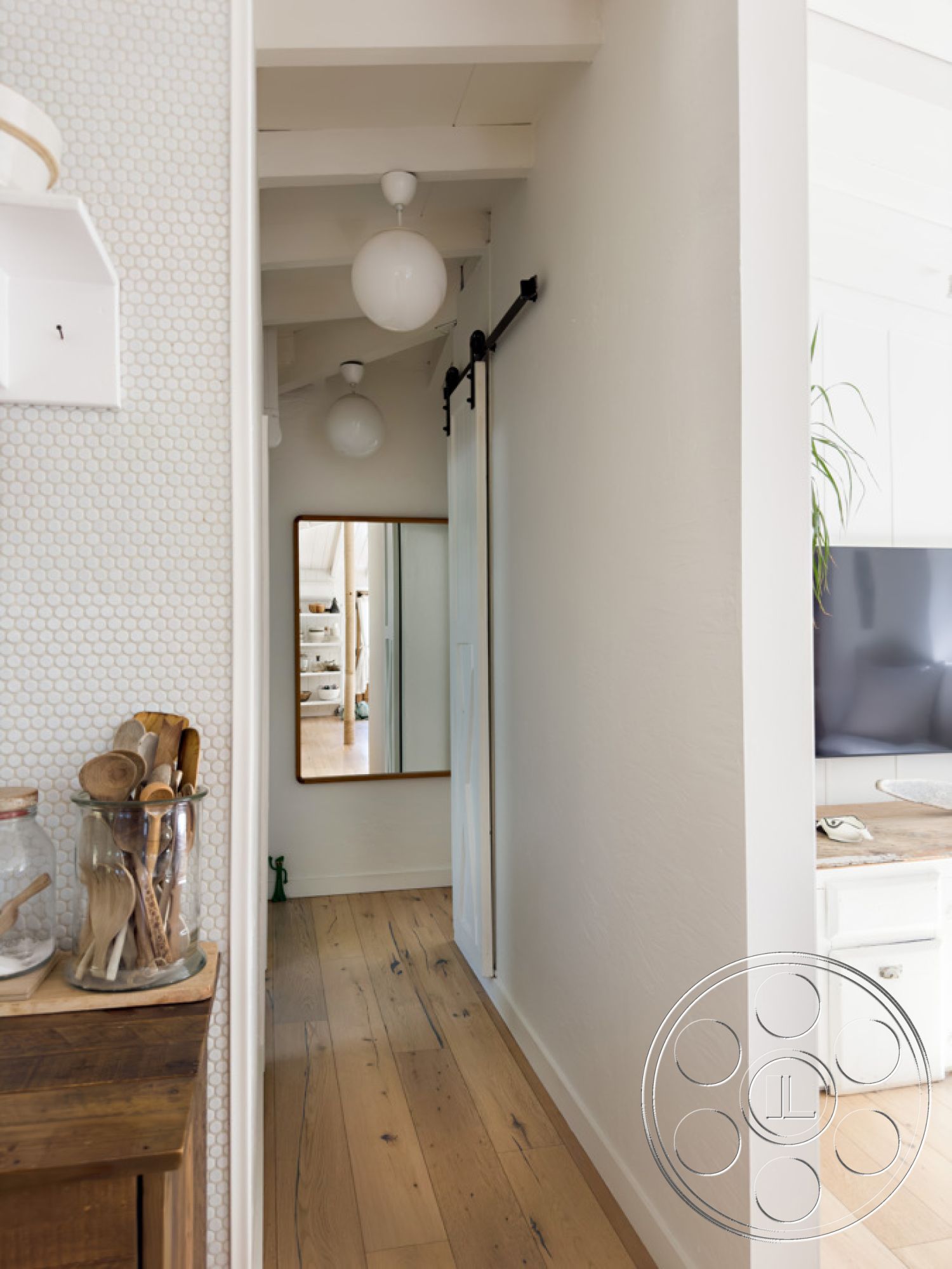 Ranch 33 - neutral color palette, minimalist design, modern pendant lighting, sustainable materials, bright and airy atmosphere, open-concept layout, sliding barn door, full-length mirror, exposed wood ceiling beams, interior hallway, hexagonal mosaic tile accent wall, unpainted drywall walls, natural oak hardwood flooring