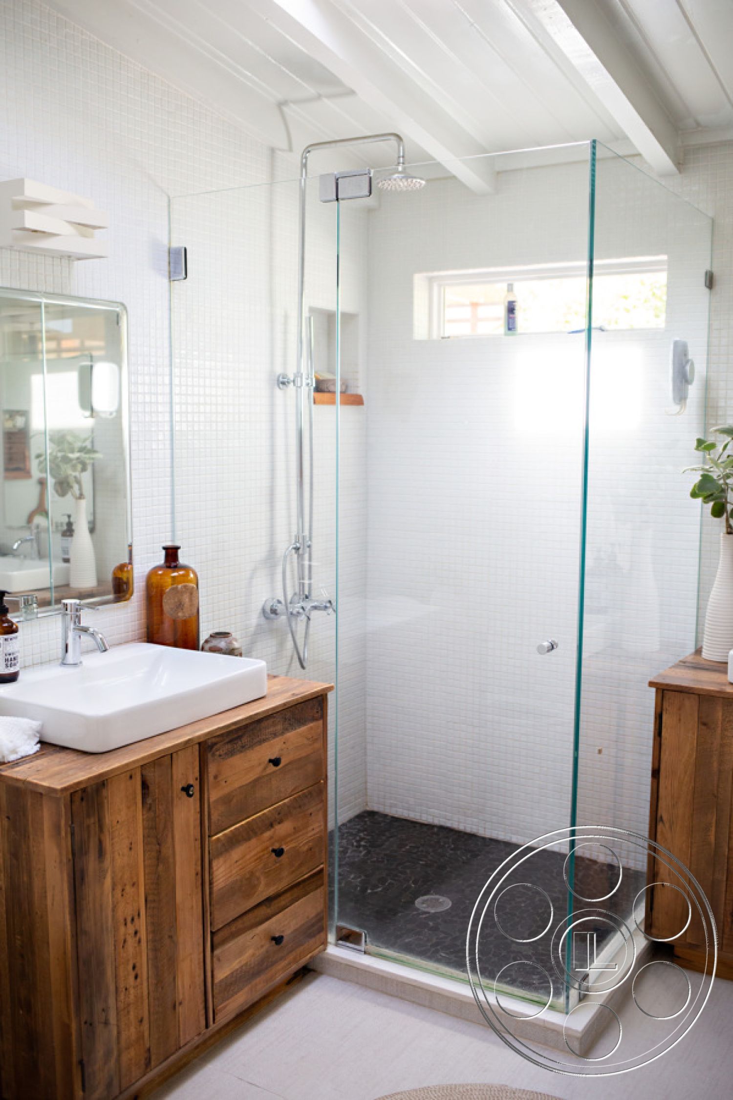 Ranch 33 - neutral color palette, glass shower enclosure, exposed beam ceiling, natural light from window, minimalist decor elements, interior bathroom, chrome faucet fixtures, modern showerhead, white mosaic tile walls, reclaimed wood vanity cabinet, black slate shower floor, single sink countertop, stylish storage jars