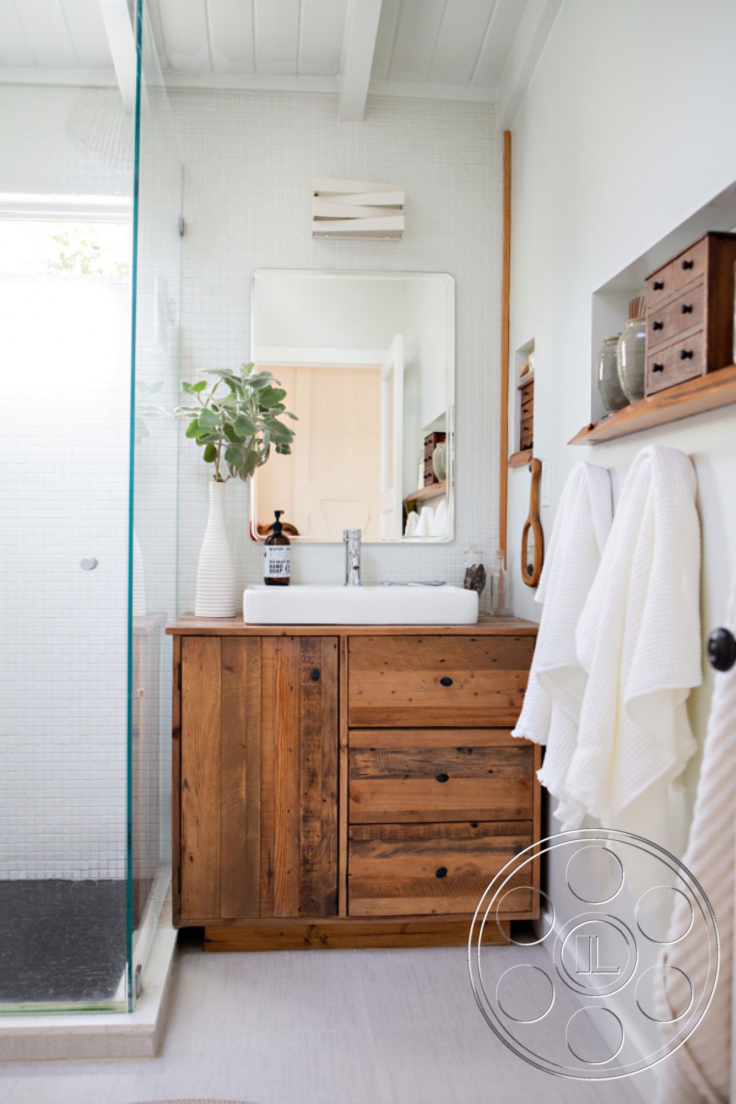 Ranch 33 - neutral color palette, minimalist design, glass shower enclosure, open shelving, sconce lighting, vase with greenery, white ceramic sink, wooden storage boxes, light wood ceiling beams, natural light interior, interior bathroom, white painted walls, functional bathroom layout, textured cotton towels, black slate shower floor, reclaimed wood vanity, mosaic tile shower walls, sleek bathroom mirror, modern faucet fixture