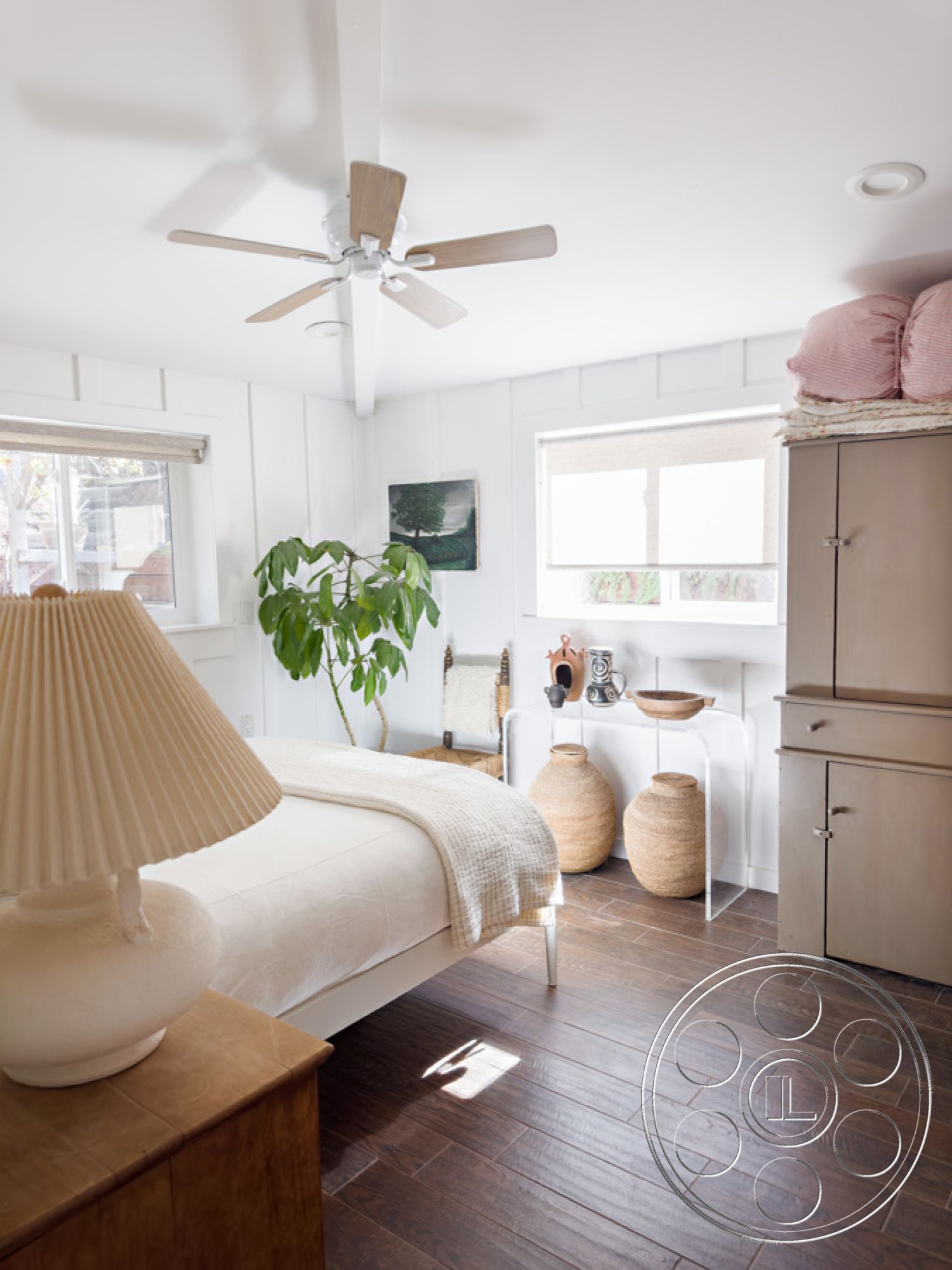 Ranch 33 - natural light, textured bedding, ceiling fan, exposed wood ceiling beams, interior bedroom, modern minimalist design, hardwood bedroom floors, white painted walls, built-in shelving unit, large windows with natural light, plant accent decor, woven baskets decor, decorative wooden bowl, light natural color palette, traditional style bedroom furnishings