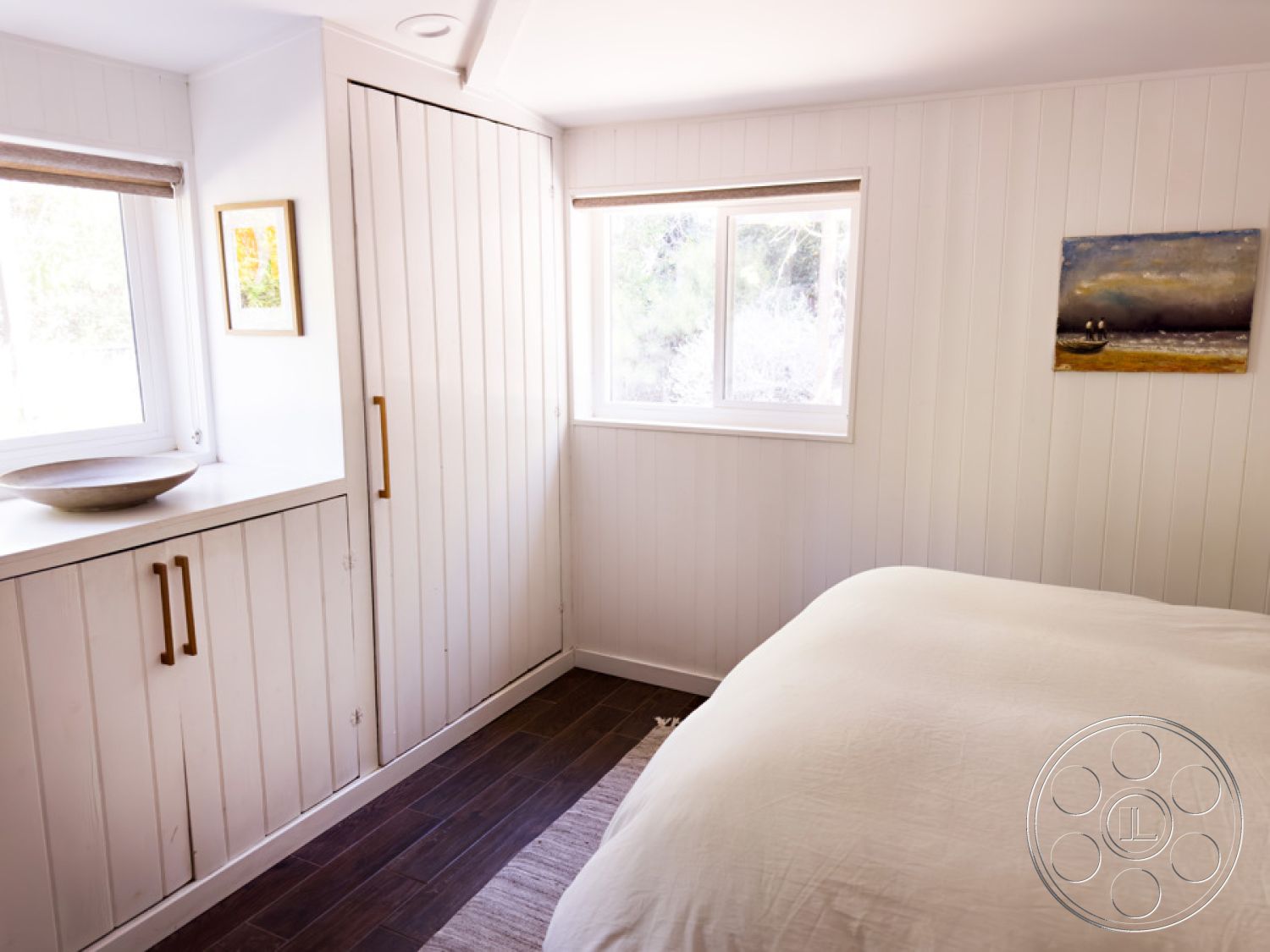 Ranch 33 - textured area rug, natural wood accents, artistic wall decor, white shiplap walls, soft lighting fixtures, cozy reading nook, modern farmhouse style, minimalist interior design, hardwood bedroom floors, interior bedroom setting, built-in storage cabinets, large sliding windows, neutral bedding with texture, clean and simple shapes