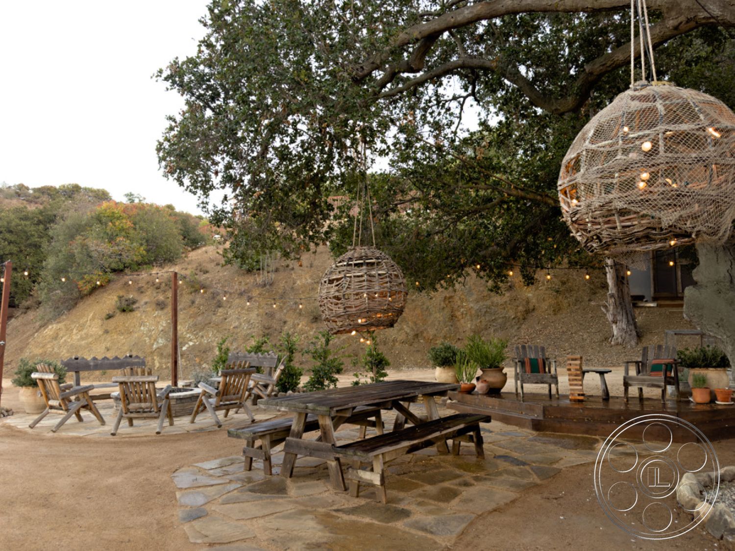 Ranch 33 - outdoor seating area, exposed wooden beams, casual dining area, soft ambient lighting, outdoor entertaining space, natural stone walls, relaxed outdoor ambiance, wooden picnic tables, decorative potted plants, earth-toned decor, natural landscape view, circular fire pit, rustic garden setting, stone patio flooring, open hillside location, woven hanging lights, patio lounge chairs, country-style atmosphere, tree-shaded area, wood deck platform