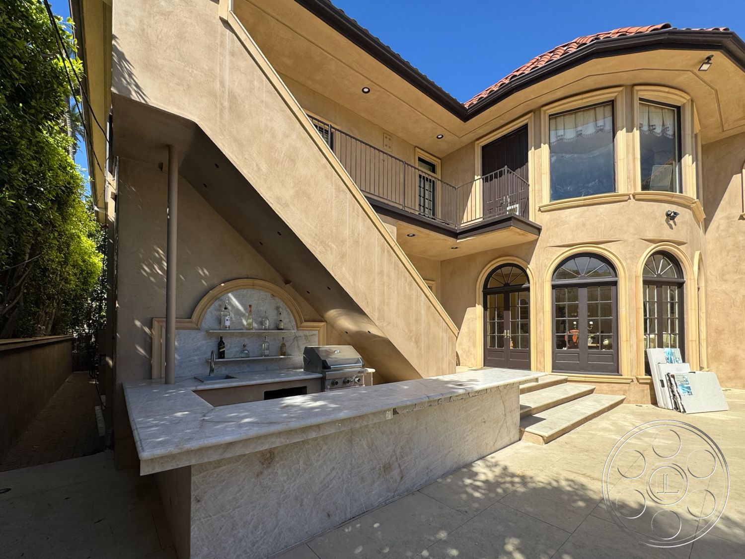 Mansion 146 - exterior stucco wall finish, interior floor-to-ceiling windows, interior warm neutral color palette, exterior stone steps, exterior contemporary architectural style, exterior curved staircase, exterior concrete backyard patio, exterior marble outdoor kitchen countertop, exterior arched windows, exterior black wrought iron railings, exterior double door entry with glass panels, interior vaulted ceiling with crown molding, interior high ceiling living room, exterior outdoor grilling area, exterior tile flooring, exterior lush greenery surrounding area, exterior outdoor entertaining space, exterior built-in kitchen features, exterior light fixture accents, exterior natural stone steps leading up