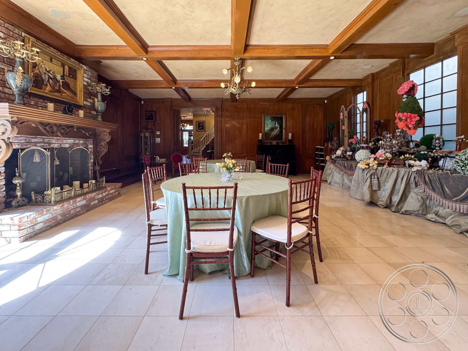 Mansion 146 - neutral color palette, spacious layout, artwork on wall, round dining table, textured plaster ceiling, traditional architectural style, chiavari chairs, decorative floral arrangements, exposed brick fireplace surround, large windows with natural light, wood paneling walls, glass chandelier lighting, marble flooring in dining area, coffered ceiling with wood beams