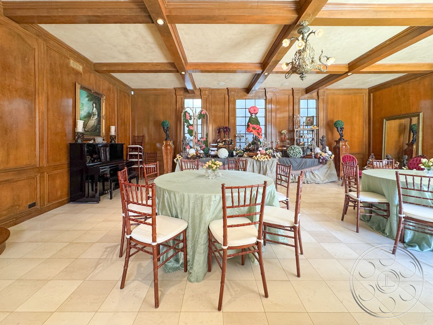 Mansion 146 - black grand piano, soft color palette, exposed wood beam ceiling, mirror accent wall, interior wood paneling walls, marble floor tiles, traditional chandelier lighting, formal dining space, white textured plaster ceiling, dark wood dining furniture, round dining tables with tablecloths, large windows with decorative framing, elegant party decor, floral centerpiece arrangements, classic artwork on walls, ceramic decorative accents