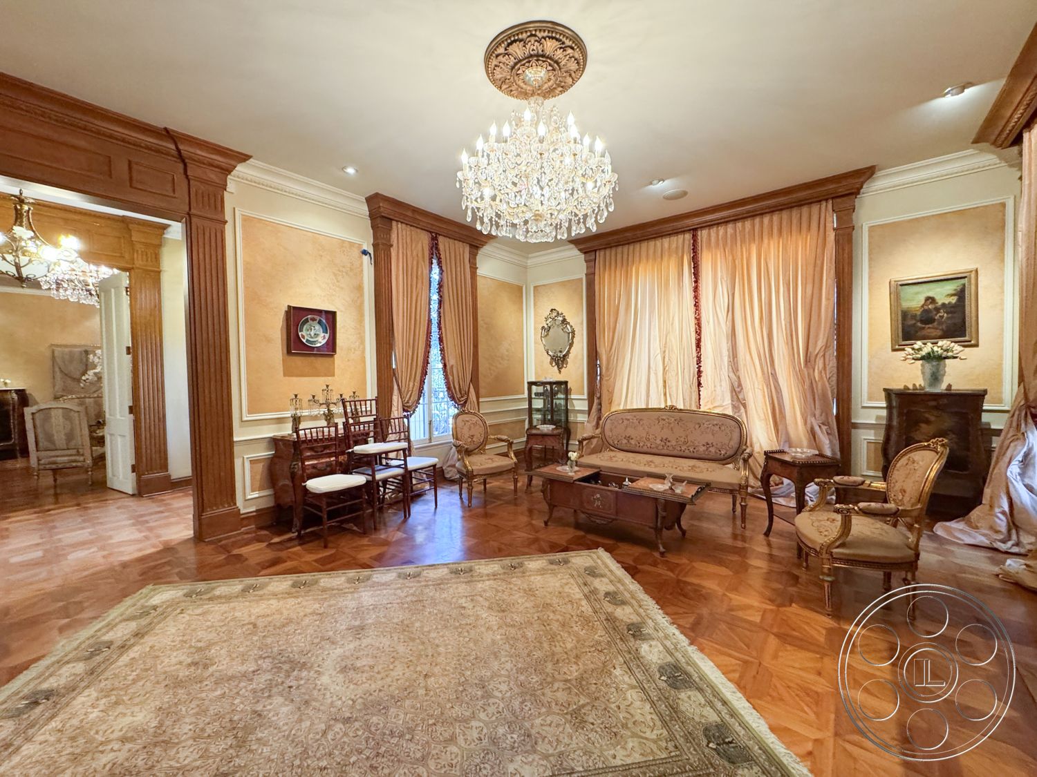 Mansion 146 - cozy reading nook, decorative wall paneling, textured wallpaper accent wall, exposed wood ceiling details, beige painted walls, intricate ceiling medallion, interior hardwood parquet floors, ornate crystal chandelier lighting, gold leaf crown molding details, luxurious drapery window treatments, antique velvet seating furniture, gilded mirror decor, traditional ornate coffee table, vintage artwork wall decor, classic wooden side tables, plush area rug flooring, elegant framed paintings, formal sitting area, historical architectural design, Victorian-style furnishings