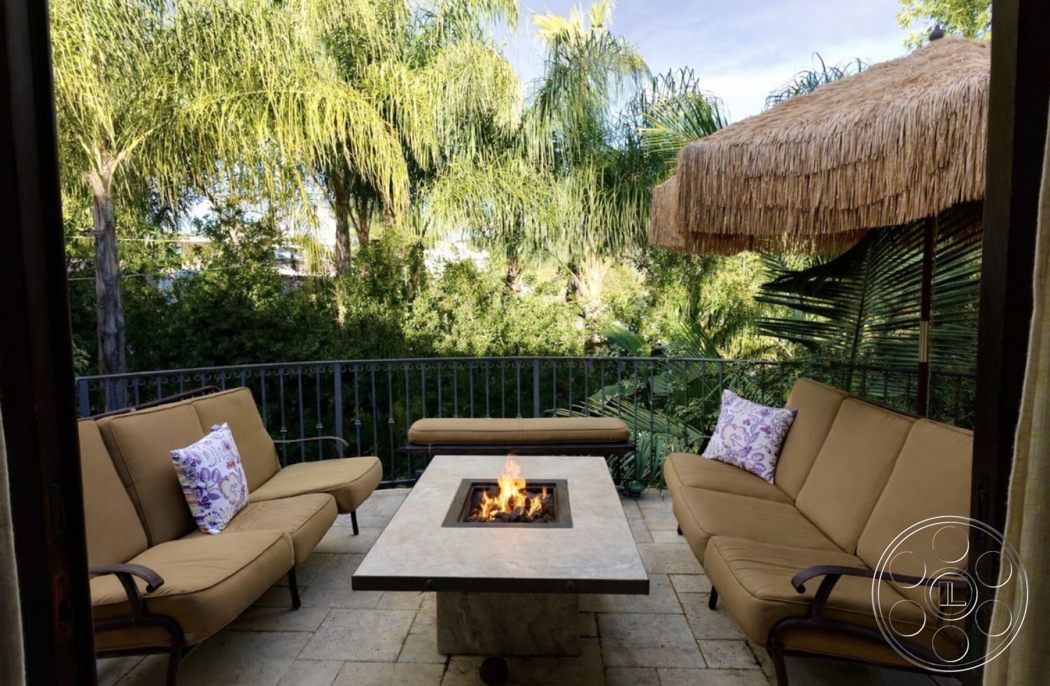 Medit 167 - natural stone flooring, outdoor entertaining space, garden seating area, open-air lounge, exterior patio area, modern outdoor design, palm tree surroundings, tropical landscaping view, metal balcony railing, rectangular fire pit table, concrete fire pit surface, woven straw umbrella, tan outdoor sofa cushions