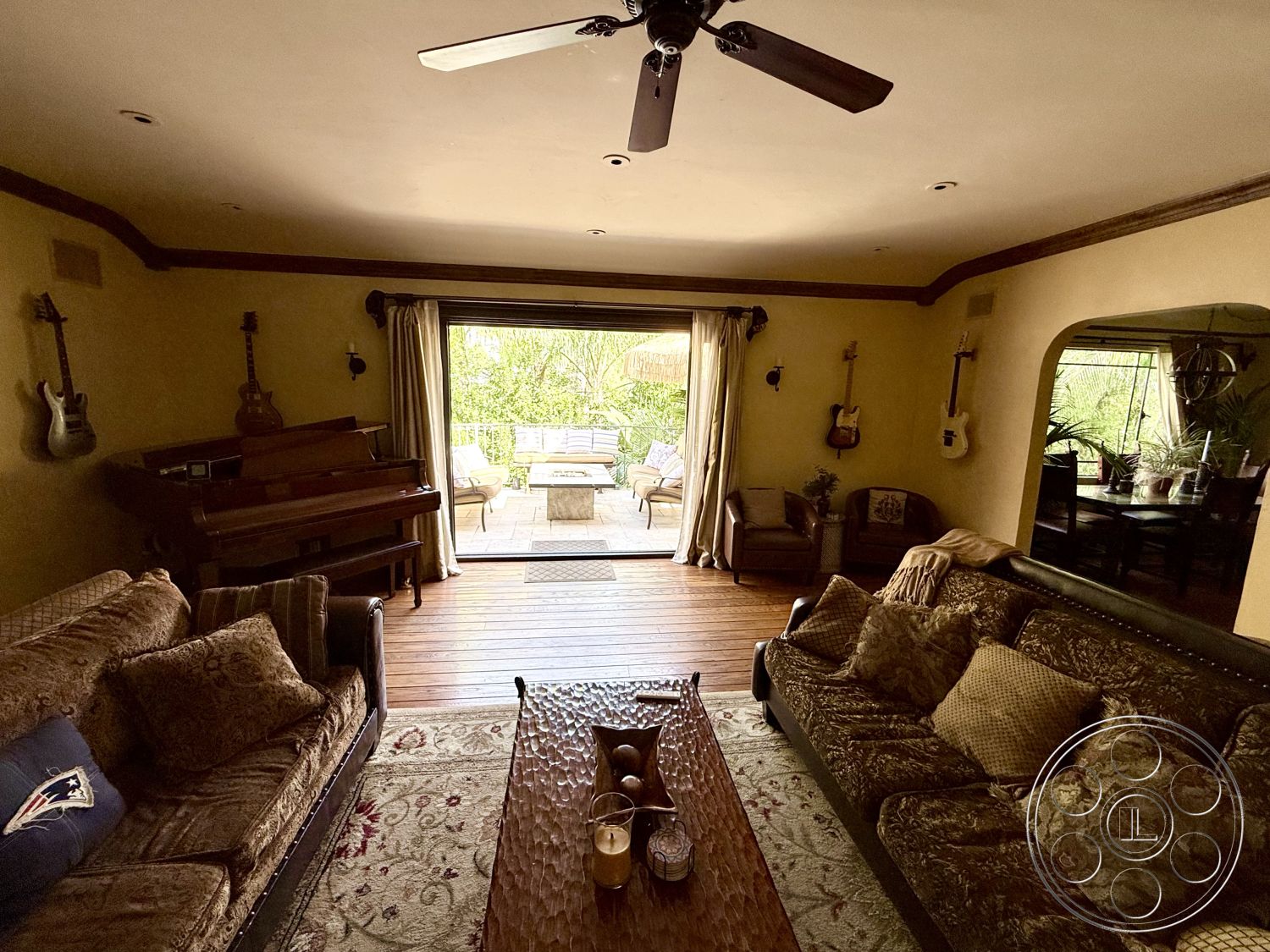 Medit 167 - natural light, open layout, glass coffee table, textured plaster walls, patterned area rug, wooden ceiling fan, large sliding glass doors, recessed lighting fixtures, interior living room, decorative plant accents, coffered ceiling details, relaxed modern aesthetic, L-shaped sectional sofa, oak hardwood flooring, acoustic piano, guitar wall decor, patio access area