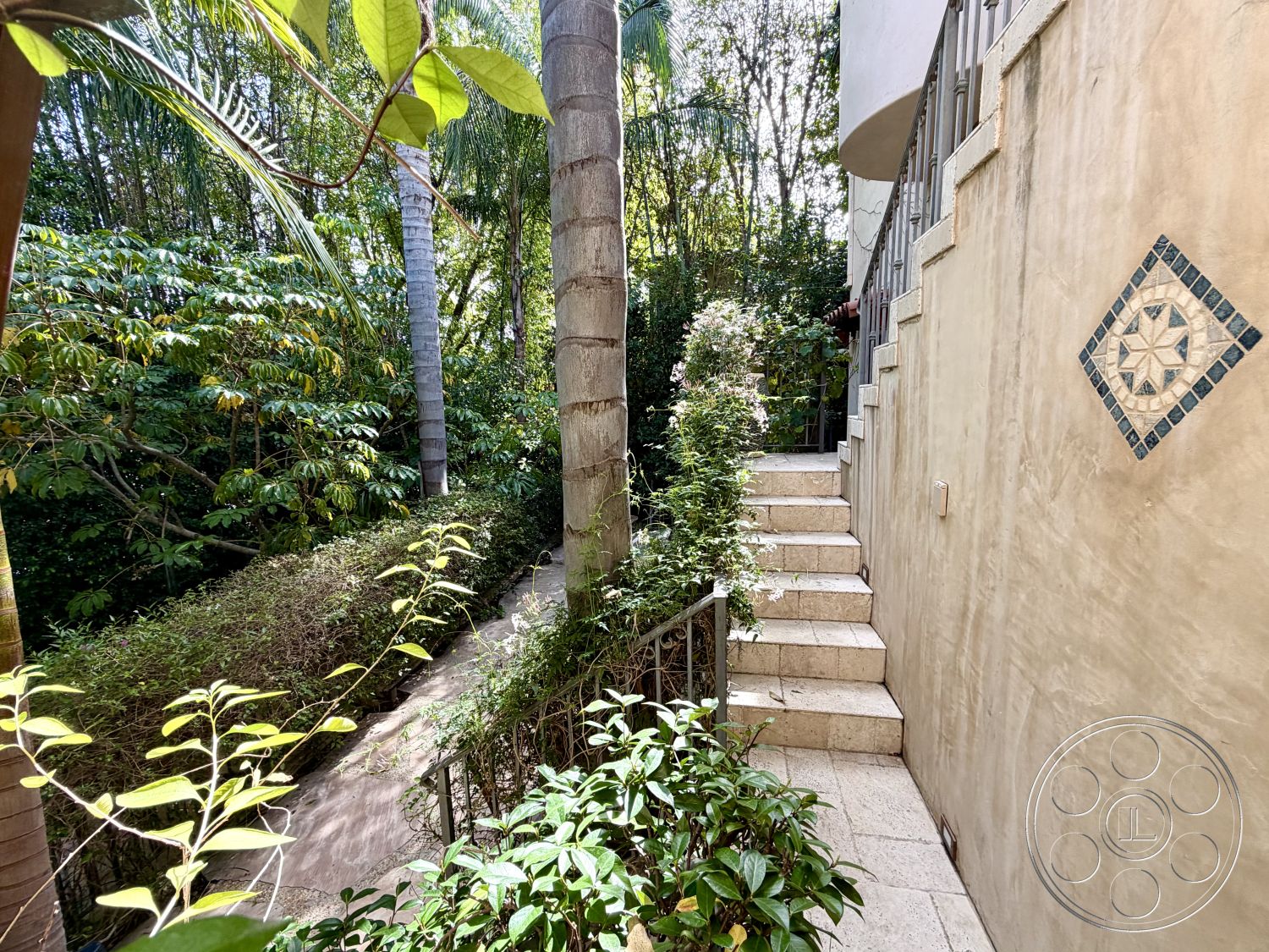 Medit 167 - surrounding greenery, fenced garden area, tropical landscape, tropical foliage, natural stone steps, textured plaster wall, lush garden setting, metal stair railings, exterior stairs, decorative tile detail, patio path, interior stair transition, staircase leading up, hierarchical landscape design