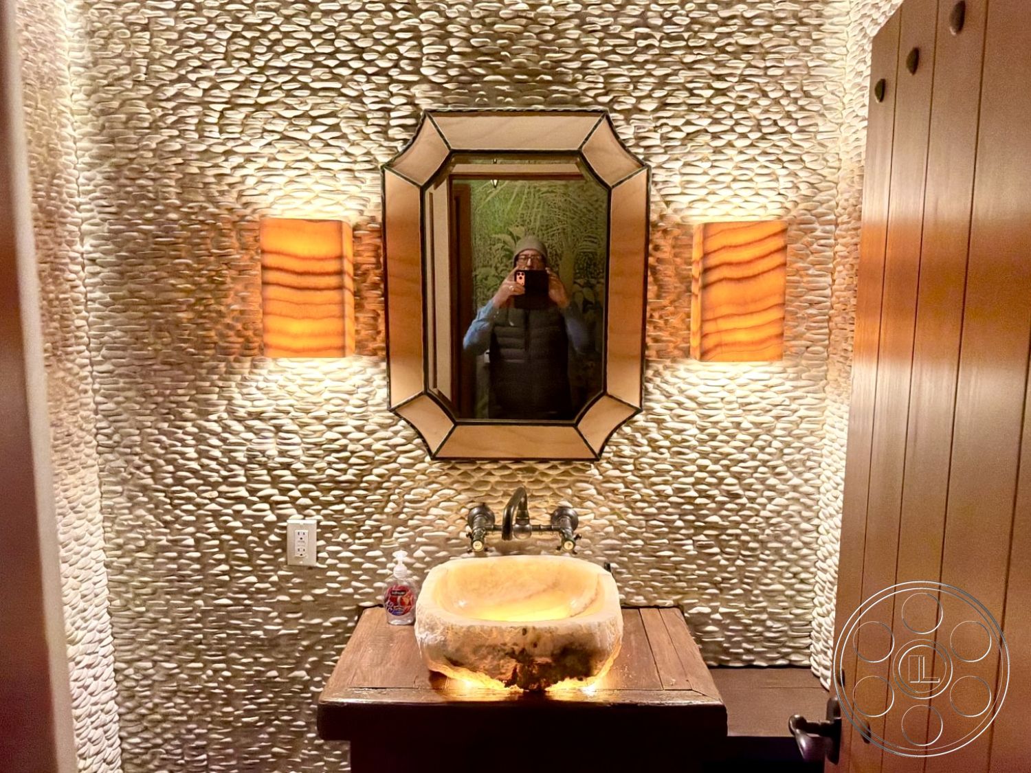 Medit 167 - natural materials, modern fixtures, ambient lighting, decorative wall accents, minimalist bathroom design, textured stone feature wall, contemporary wall lighting, wooden bathroom vanity, natural pebble wall texture, handcrafted stone sink, backlit wall sconces, framed mirror with geometric accents, warm wooden door, rustic bathroom decor