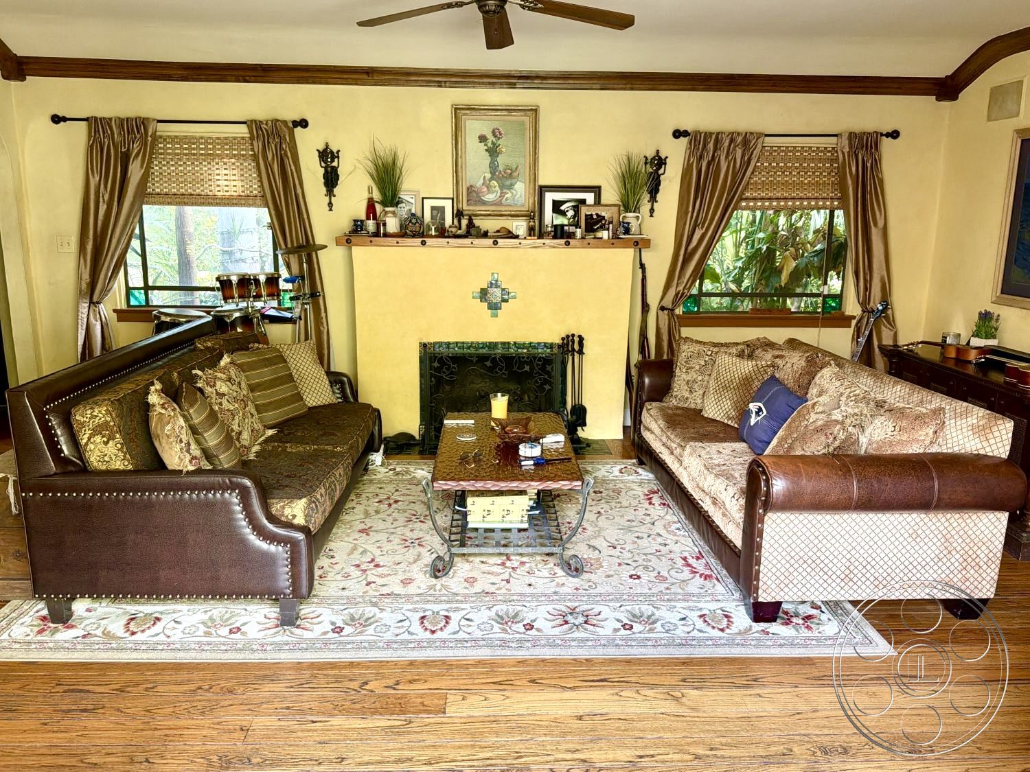 Medit 167 - natural light from large windows, ornate wall decor, decorative throw pillows, wood window frames, textured fabric curtains, exposed wood ceiling beams, hardwood living room floors, interior living room, traditional area rug, stone fireplace wall, traditional crown molding details, cream-colored plaster walls, leather upholstered sofa, brass finish lighting fixtures, wooden coffee table with metal accents