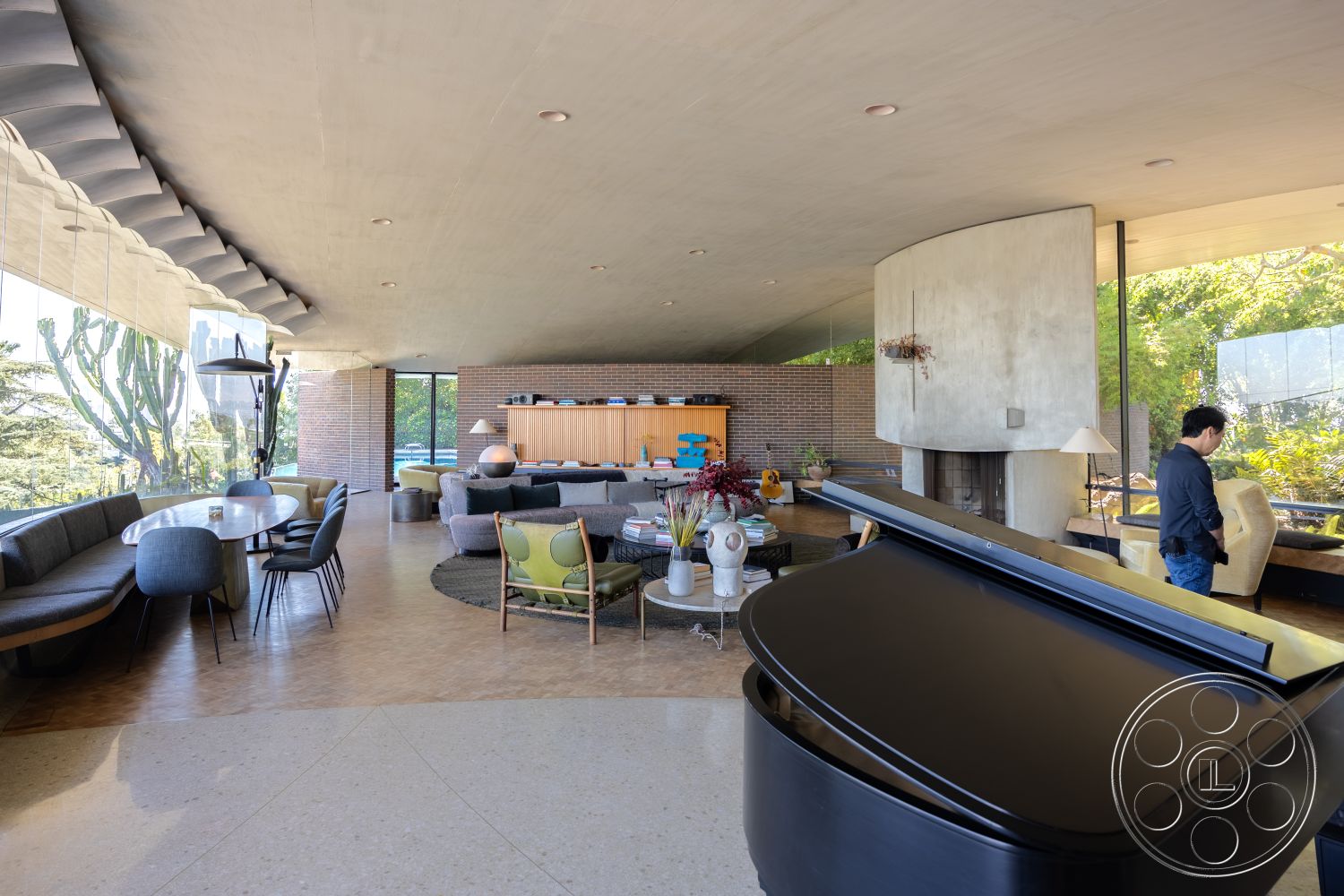 Silvertop House - polished concrete flooring, Mid-Century Modern architecture, urban setting, round dining table, concrete ceiling, textured wall treatments, soft color palette, open-concept design, integrated lighting fixtures, natural light-filled living space, glass window walls, exposed brick interior walls, curved lounge seating, built-in wood cabinetry, modern upholstered chairs, piano in living area, minimalist dining area decor, architectural landscape view, exterior greenery landscape