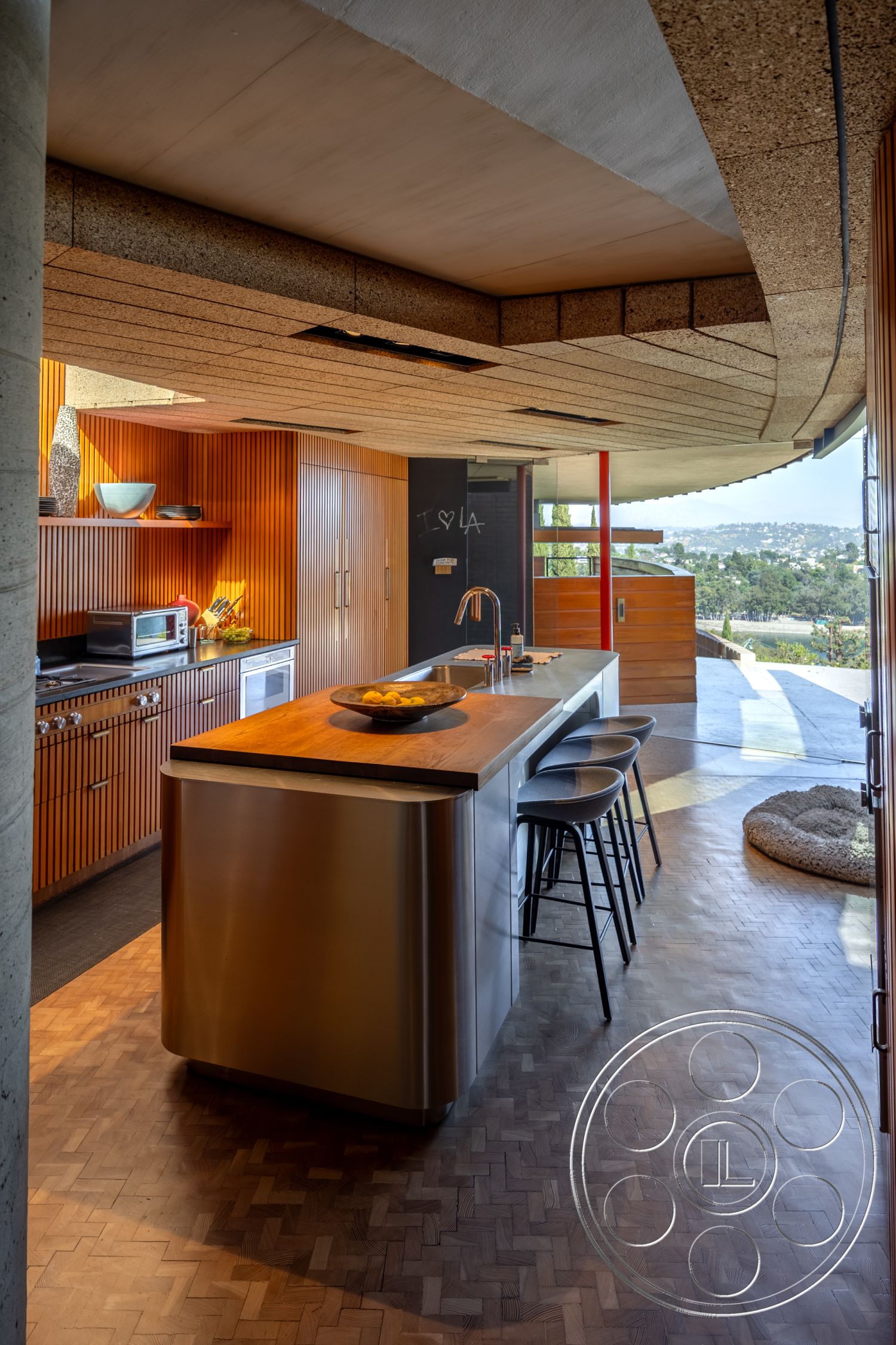 Silvertop House - floor-to-ceiling windows, warm wood accents, minimalist kitchen design, integrated kitchen appliances, rustic modern style, herringbone patterned hardwood flooring, interior kitchen with cork ceiling panels, stainless steel kitchen island, vertical wood paneling kitchen cabinets, modern kitchen with open layout, contemporary kitchen fixtures, large glass sliding door with city view, indirect lighting under cabinets, breakfast bar with metal stools, textured ceiling design, concrete structural elements, panoramic view kitchen, kitchen with natural light