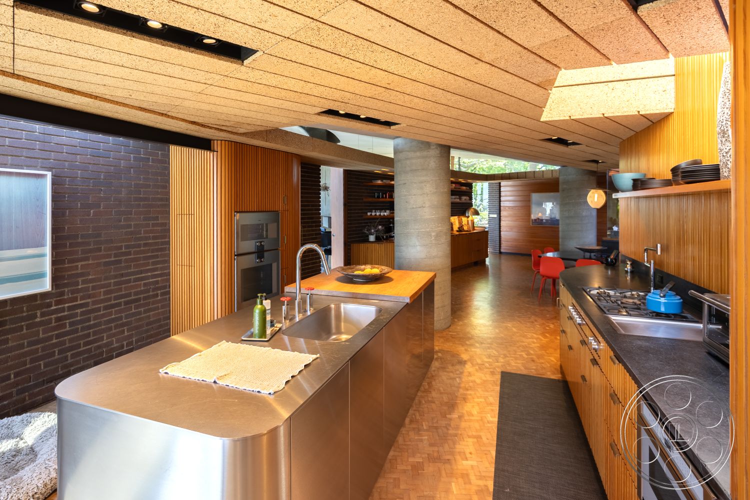 Silvertop House - dark stone countertop, open-concept kitchen layout, modern pendant lighting fixtures, interior kitchen with natural light, curved ceiling design, contemporary kitchen cabinetry, stainless steel kitchen island, exposed brick kitchen walls, light wood paneling kitchen accents, raw concrete support pillars, vintage tile kitchen backsplash, parquet hardwood kitchen flooring, industrial-style kitchen appliances, chef's kitchen with island seating, spacious gathering area adjacent to kitchen