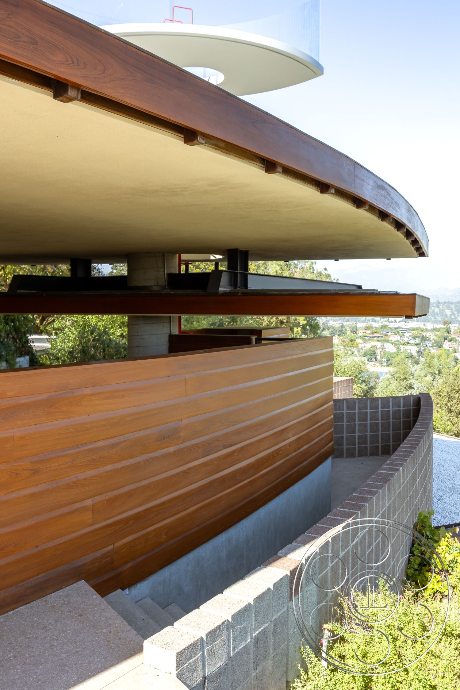 Silvertop House - landscaped surroundings, exposed concrete walls, modern architectural style, contemporary exterior, scenic hillside view, horizontal wood siding, outdoor garden setting, floating concrete steps, concrete stair treads, interior and exterior integration, textured stone retaining wall, wood beam soffit, curved wooden overhang, cantilevered balcony design
