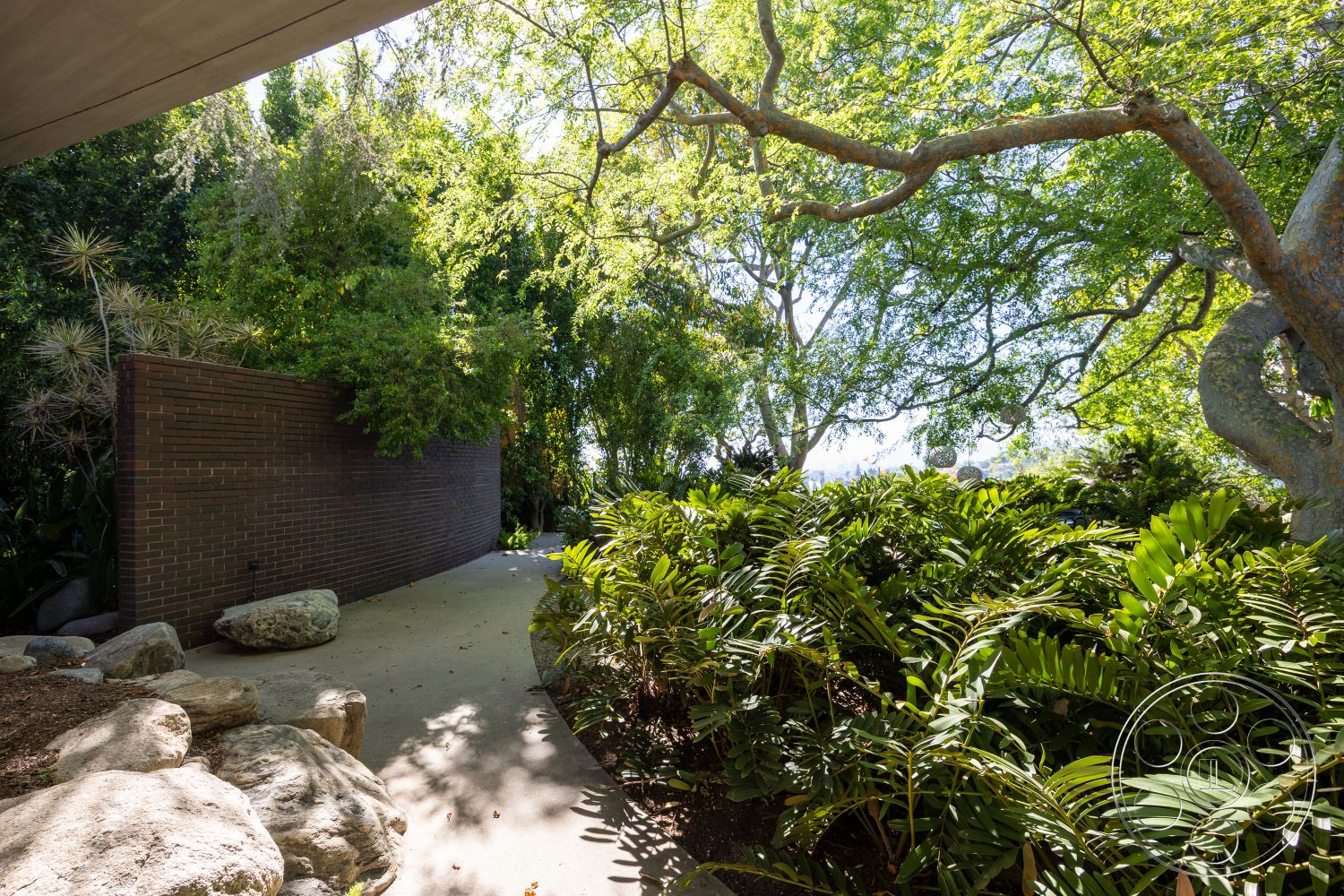 Silvertop House - natural stone accents, modern architecture, concrete pathway, urban outdoor space, environmentally integrated design, smooth concrete finish, organic landscape design, landscaped garden area, exterior brick wall, textured brick surface, lush tropical foliage, shaded tree canopy, sustainable outdoor elements, nature-inspired surroundings