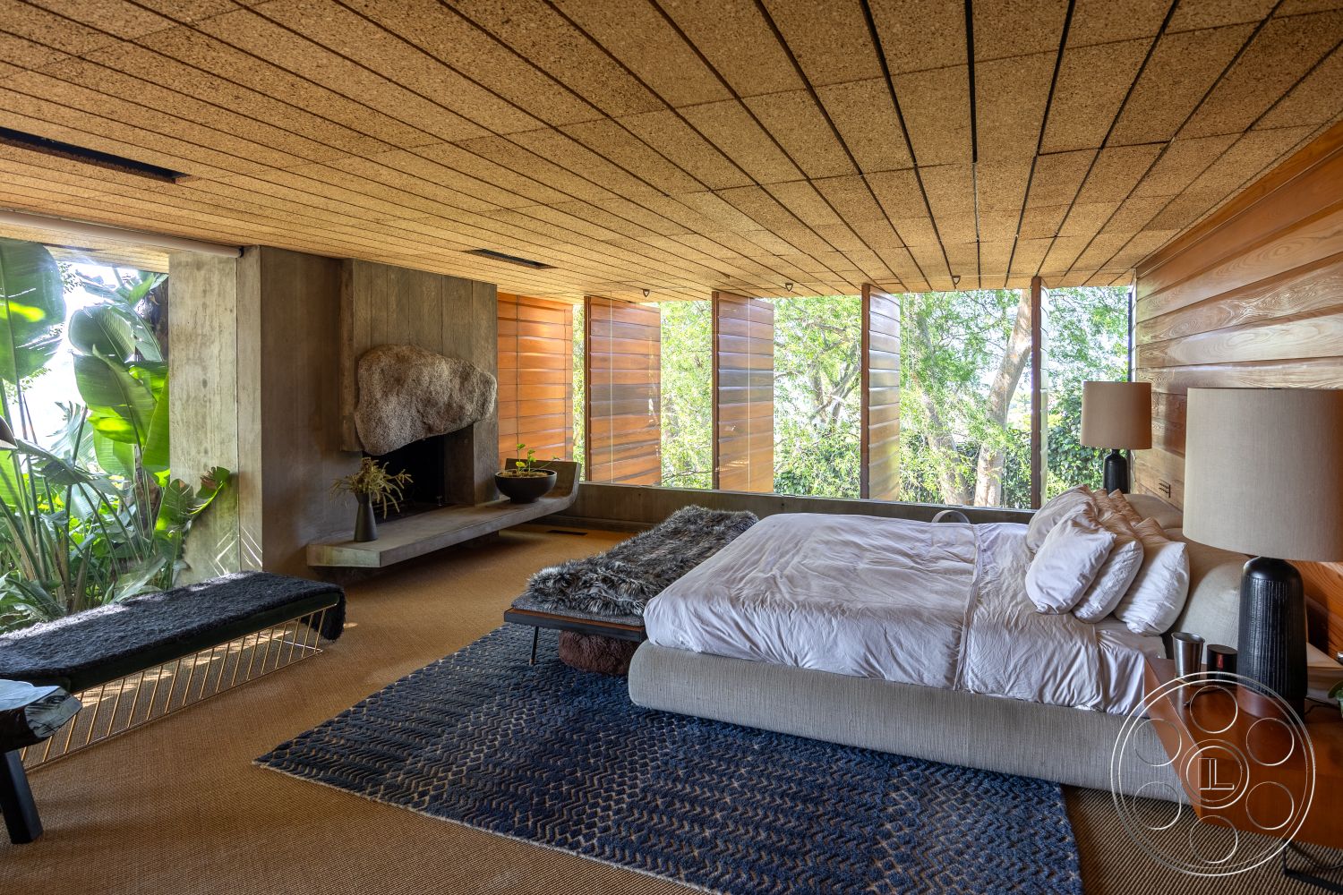 Silvertop House - textured area rug, open floor plan, exposed concrete walls, large floor-to-ceiling windows, natural landscape view, contemporary decor style, stone fireplace surround, urban retreat setting, wood paneling accents, soft upholstered bed frame, minimalist bed design, cork ceiling tiles, plant-filled surroundings, natural light-filled bedroom, low profile furniture