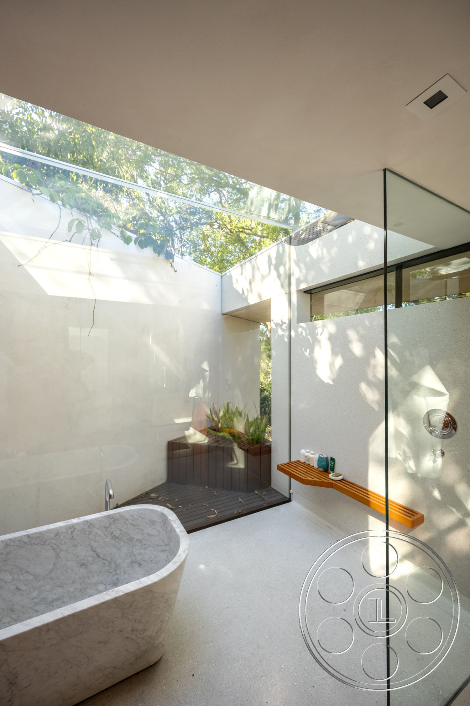 Silvertop House - interior textured plaster walls, interior polished concrete flooring, interior spa-like atmosphere, interior open concept design, interior seamless glass shower enclosure, interior contemporary architectural style, interior modern minimalist aesthetic, interior marble freestanding bathtub, interior minimalist wood shelf, interior natural light skylight, exterior lush greenery view, interior wooden decking feature