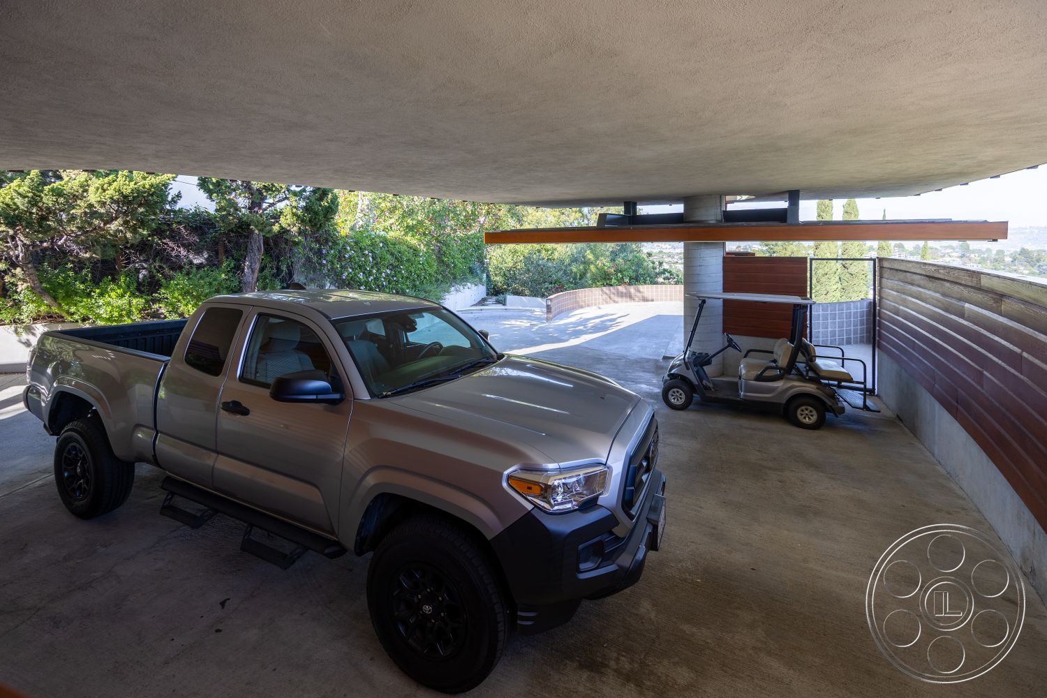 Silvertop House - smooth concrete driveway, contemporary structure, flat roof design, modern architectural details, open-air parking area, concrete ramp access, exterior concrete parking space, exposed wooden beam carport ceiling, wood paneling feature wall, garden setting with landscaping, suburban carport, outdoor golf cart parking, greenery surrounding carport