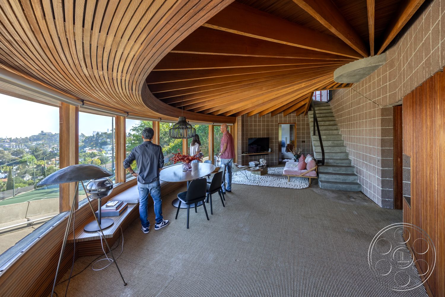 Silvertop House - neutral color palette interior, wood beam ceiling interior, textured wall surface interior, modern coffee table interior, large panoramic windows interior, open-concept living area interior, minimalist furniture interior, curved wooden ceiling panels interior, exposed concrete block walls interior, natural fiber area rug flooring interior, floating staircase with metal railing interior, round dining table wood interior, urban hillside view interior, decorative vases interior, architectural detail wood accent interior, recessed lighting features interior, glass door with wood frame interior