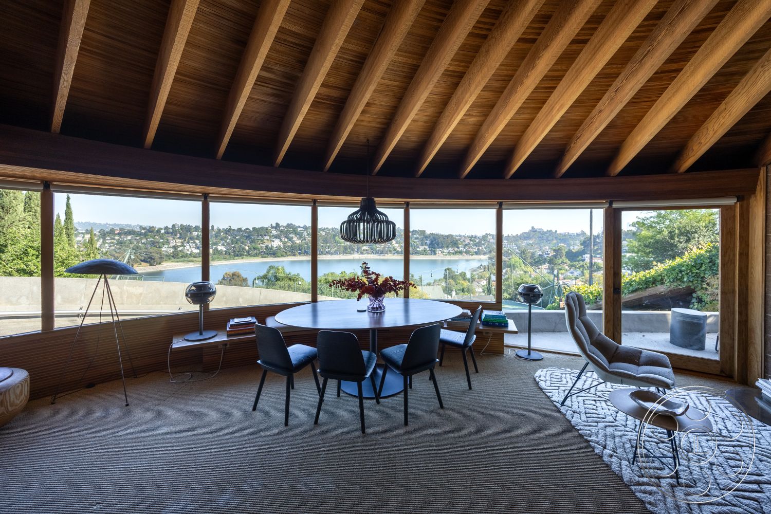 Silvertop House - interior natural light, interior wood beam ceiling, interior indoor plants, interior panoramic glass windows, exterior lush greenery, interior open floor plan layout, exterior hillside location, interior circular dining table, interior gray area rug, interior curved wooden walls, interior minimalist modern furniture, interior waterfront view, exterior contemporary design, exterior modern facade, exterior serene environment, exterior panoramic nature view