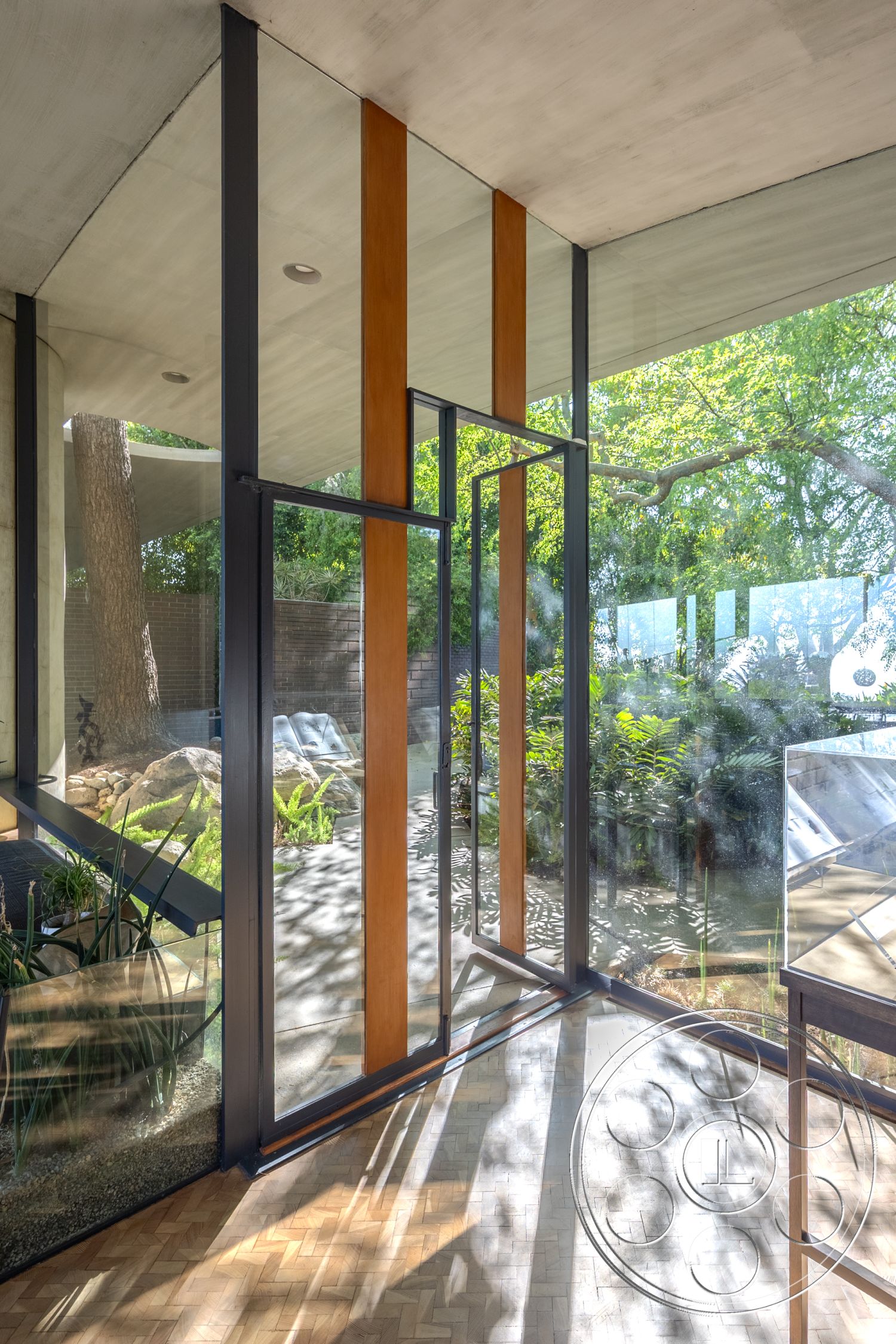 Silvertop House - natural light, minimalist design, open floor plan, glass walls, floor-to-ceiling windows, modern architectural style, concrete ceiling, exposed structural elements, parquet flooring, lush greenery setting, wood frame doors, indoor garden area, blending indoor and outdoor spaces