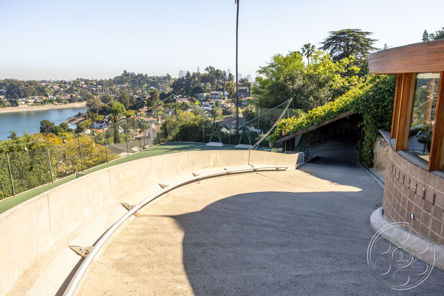 Silvertop House - landscape greenery, natural stone retaining wall, exposed aggregate concrete driveway, outdoor garden space, panoramic city skyline view, urban hillside setting, curved driveway design, sustainable landscaping features, glass railing detail, modern hillside home exterior
