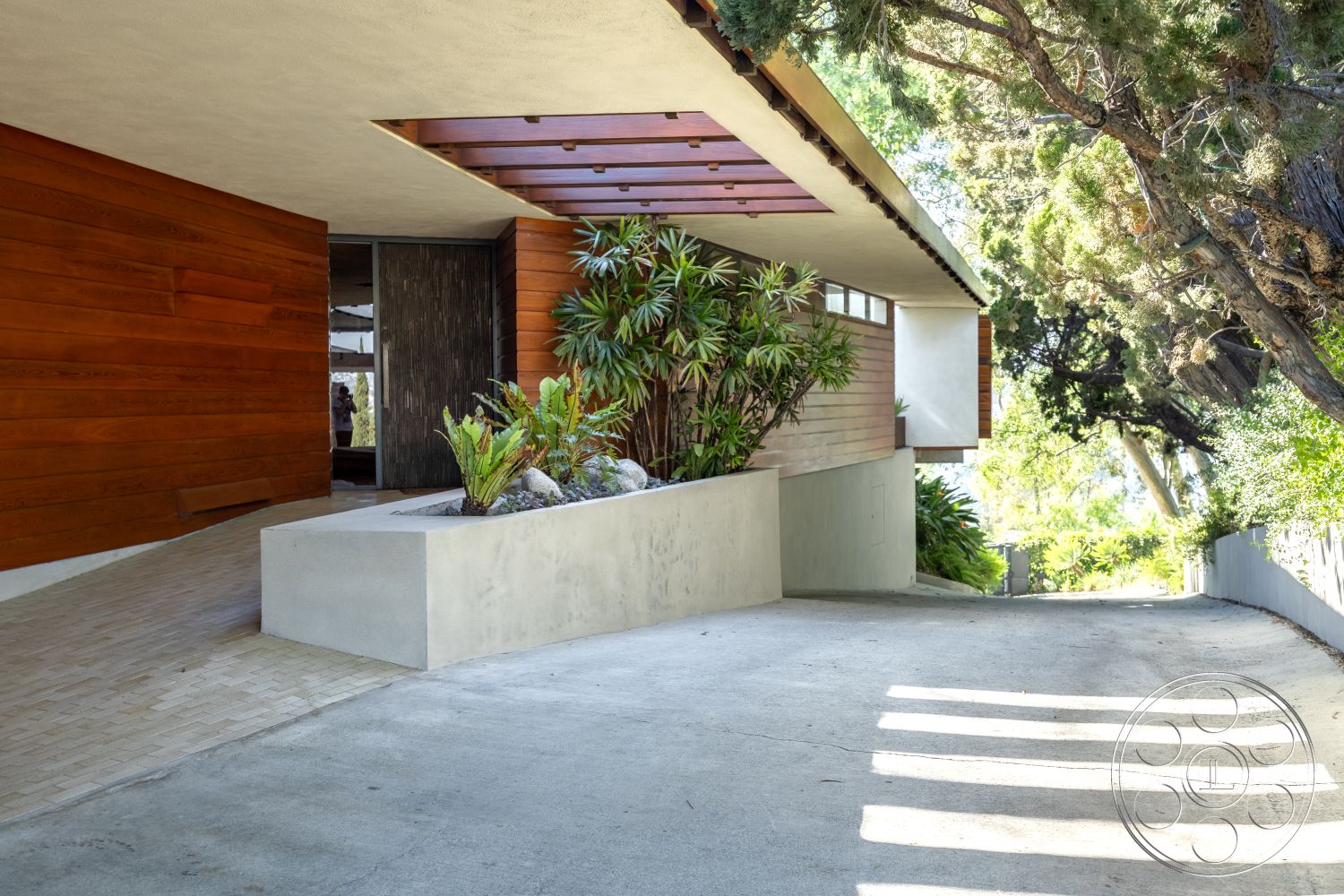 Silvertop House - natural stone accents, minimalist design, paved pathway, modern architectural style, mid-century modern elements, integrated greenery, concrete retaining wall, exterior wood paneling, sun-drenched exterior, landscaped tropical garden, open-air entrance, textured concrete driveway, curved driveway entrance, exterior concrete planter, horizontal wood slat overhang, spacious outdoor garden setting