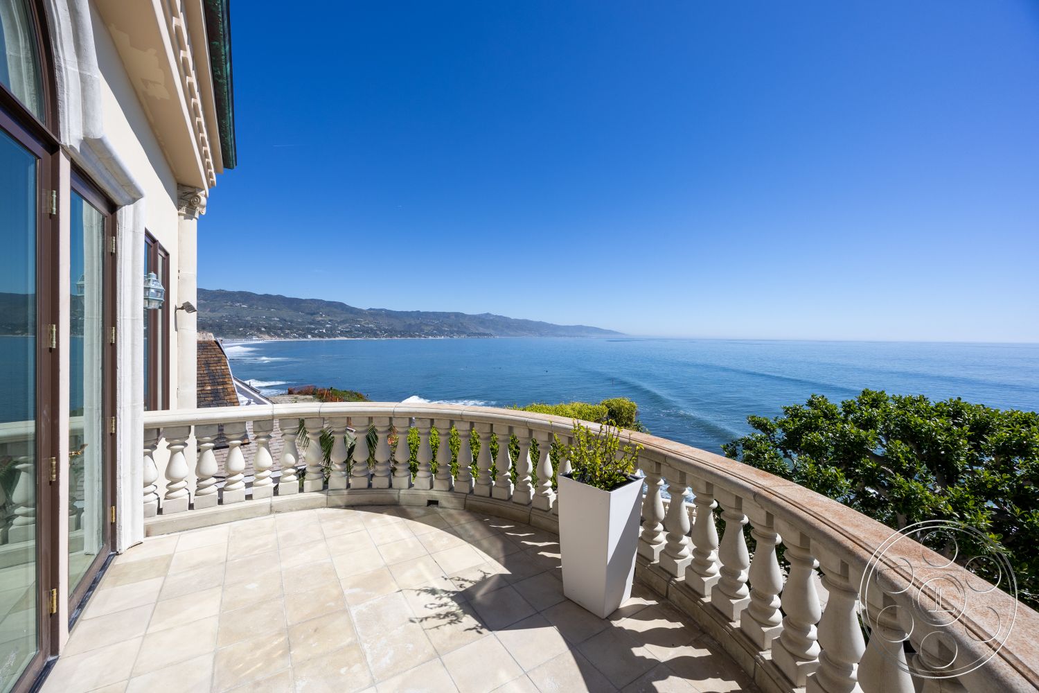 Pacifica Estate - floor-to-ceiling windows, open-air design, coastal setting, natural light flooded space, landscape planters, modern outdoor living area, marble patio flooring, curved balcony shape, interior balcony with ocean view, stone railing balustrade, luxury waterfront property, expansive oceanfront views, textured stone wall details, elegant architectural style, tiled patio edges