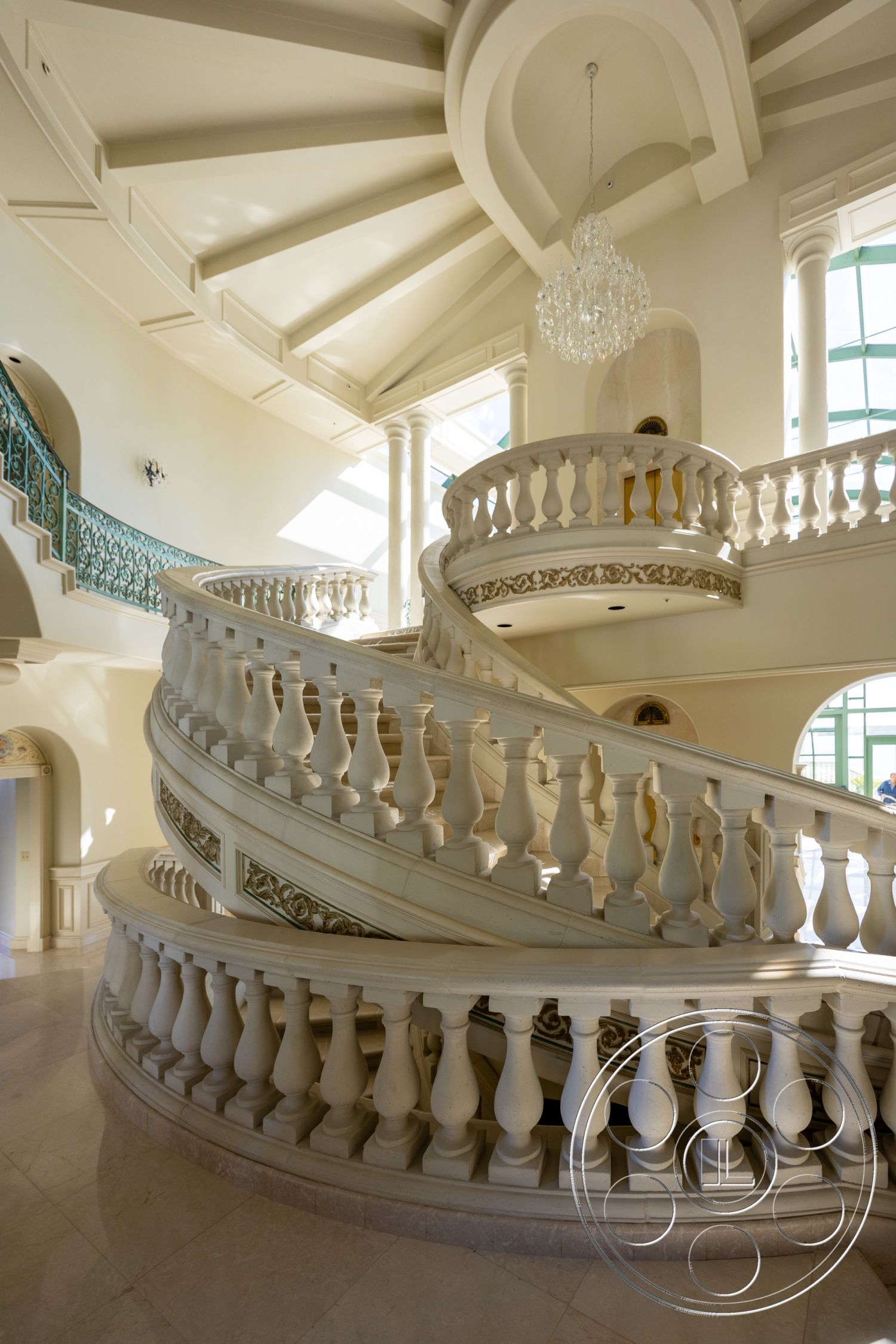 Pacifica Estate - coffered ceiling, exterior, vaulted ceiling, chandelier lighting, textured plaster walls, arched windows, ornate railing, expansive views, curved staircase, grand foyer, luxurious entryway, open interior layout, intricate molding details, smooth marble flooring, decorative balustrade, marble staircase, exposed columns, natural light fixtures, focal point chandelier