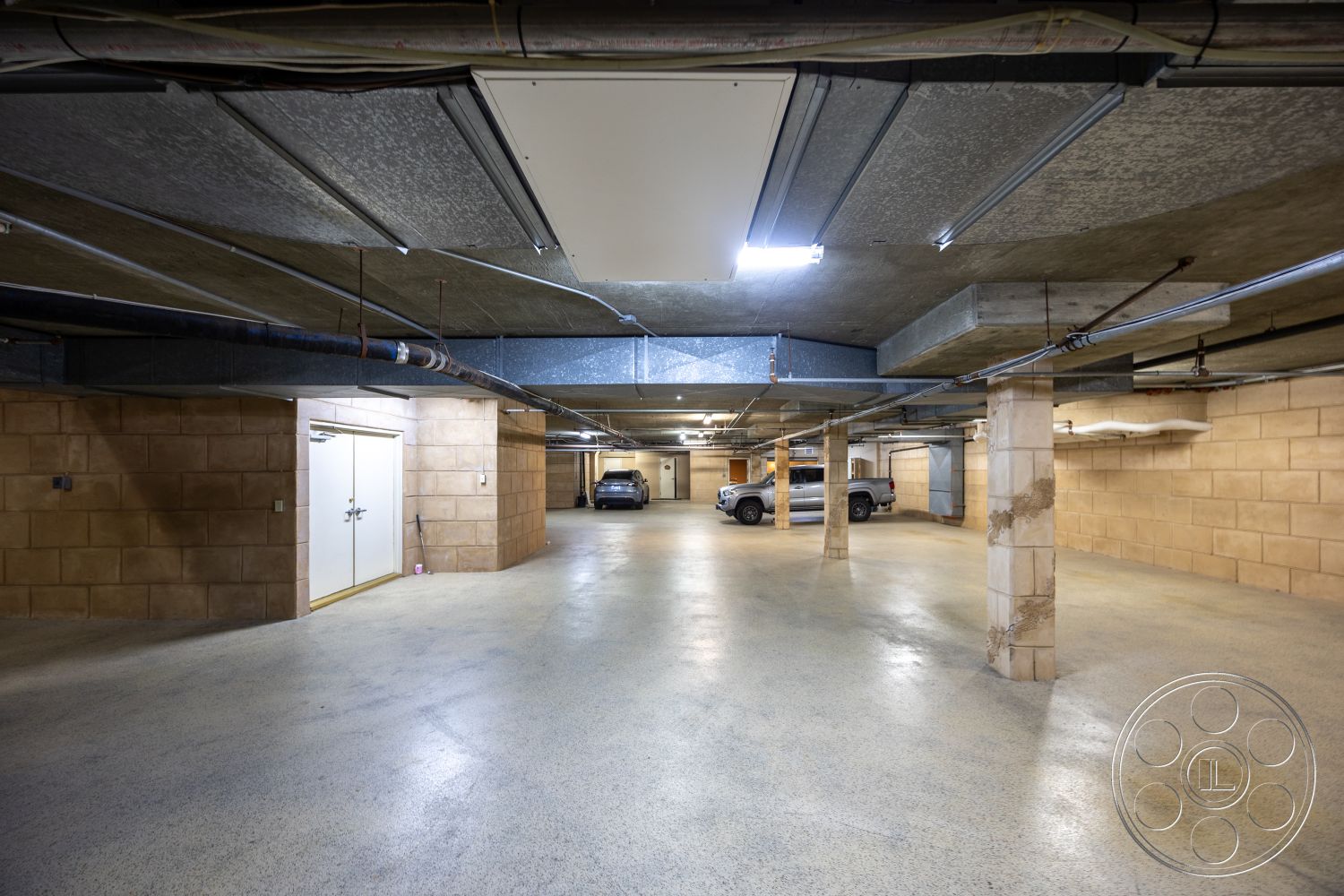 Pacifica Estate - minimalist design, polished concrete floor, exposed concrete walls, concrete block walls, steel support columns, industrial ceiling lights, functional utility area, metal overhead beams, subterranean garage space, rectangular garage layout, automotive parking area, well-lit interior, open space for vehicle storage