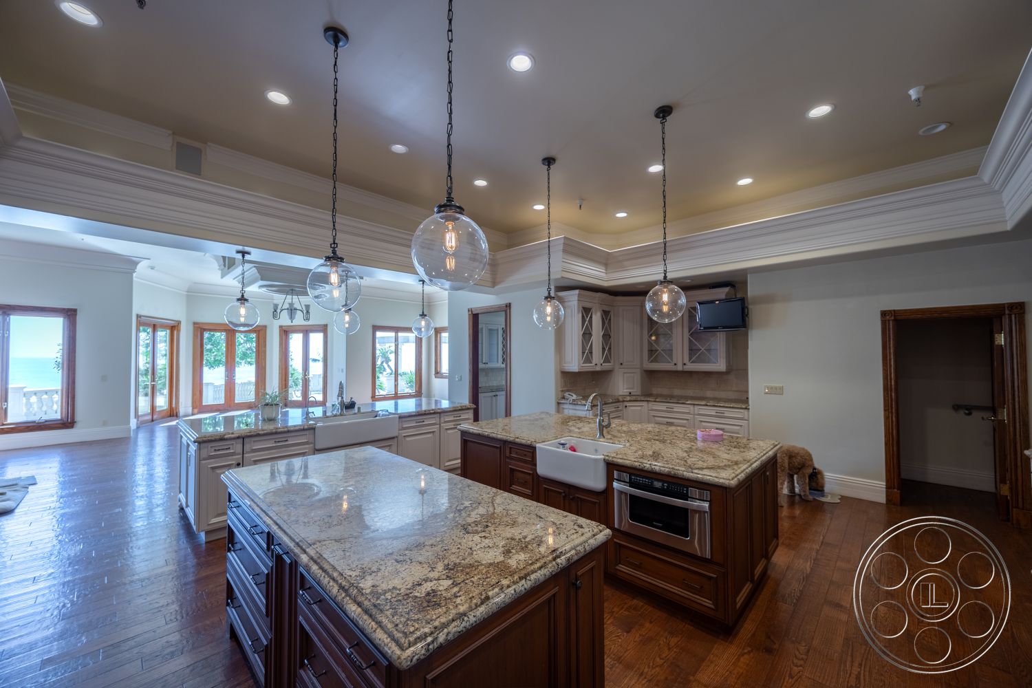 Pacifica Estate - stainless steel appliances, glass cabinet doors, modern farmhouse style, spacious dining area, pendant lighting fixtures, crown molding accents, natural light-filled space, granite kitchen countertops, hardwood kitchen floors, open-concept interior, outdoor patio access, coffered ceiling details, large windows with ocean view, kitchen island with seating, custom wooden cabinetry, double sink with faucet, walk-in pantry, bright, airy environment, luxury kitchen interior, refreshing coastal setting