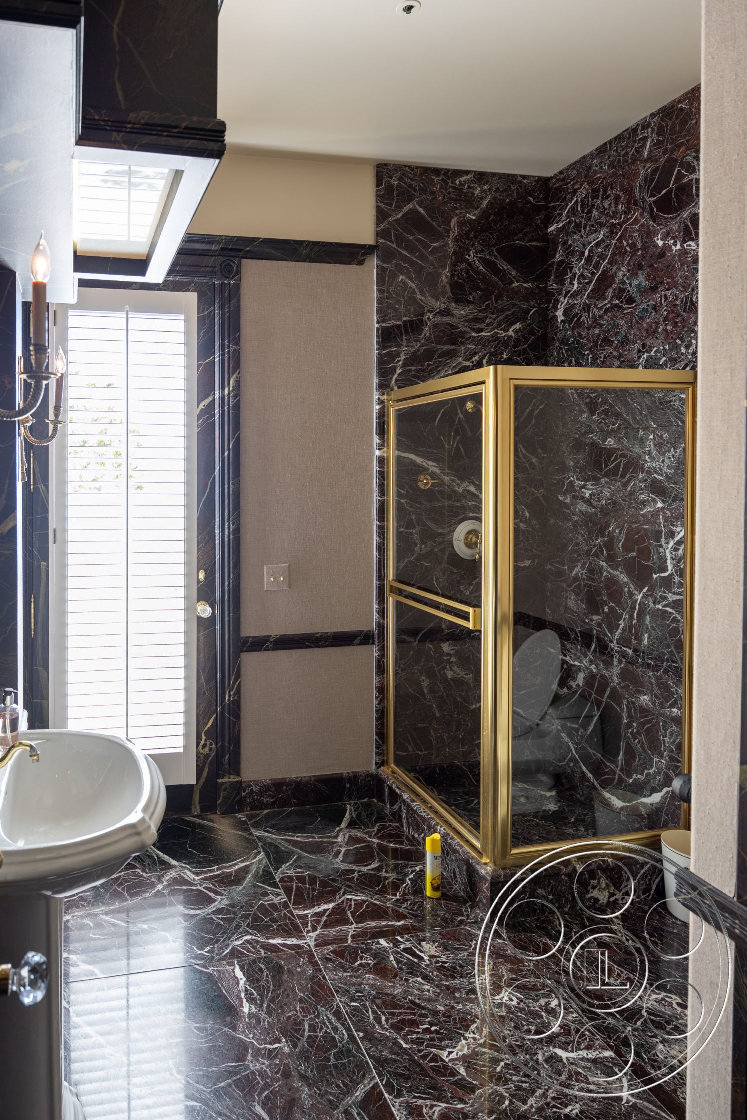 Pacifica Estate - neutral color palette, spacious layout, freestanding bathtub, glass shower enclosure, gold accents, modern lighting fixtures, elegant decor, high-end materials, contemporary bathroom, white porcelain sink, natural light from window, luxury bathroom design, detailed crown molding, decorative baseboards, polished marble bathroom flooring, dark marbled shower walls, textured wallpaper panels, black marble trim, shower with luxury finishes