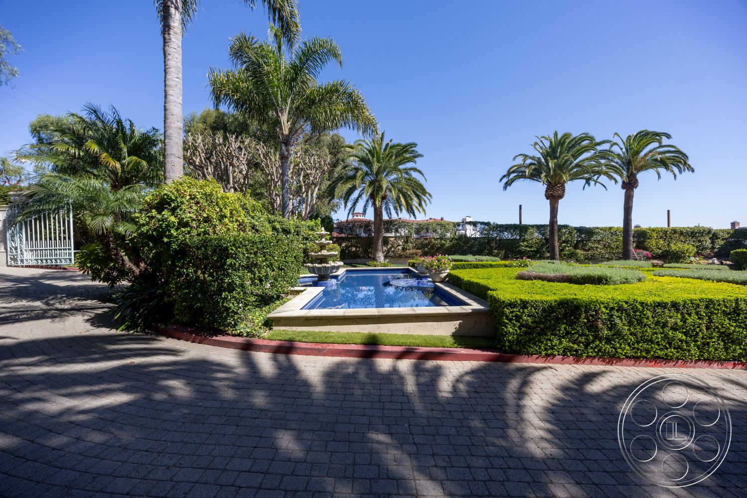 Pacifica Estate - exterior, paver driveway, curved driveway, urban garden, tropical palm trees, rectangular pool, well-manicured lawn, sunny outdoor setting, blue water pool, concrete pool border, landscaped garden with hedges, modern outdoor landscaping, cement pool border, sectioned garden beds, patio area with greenery