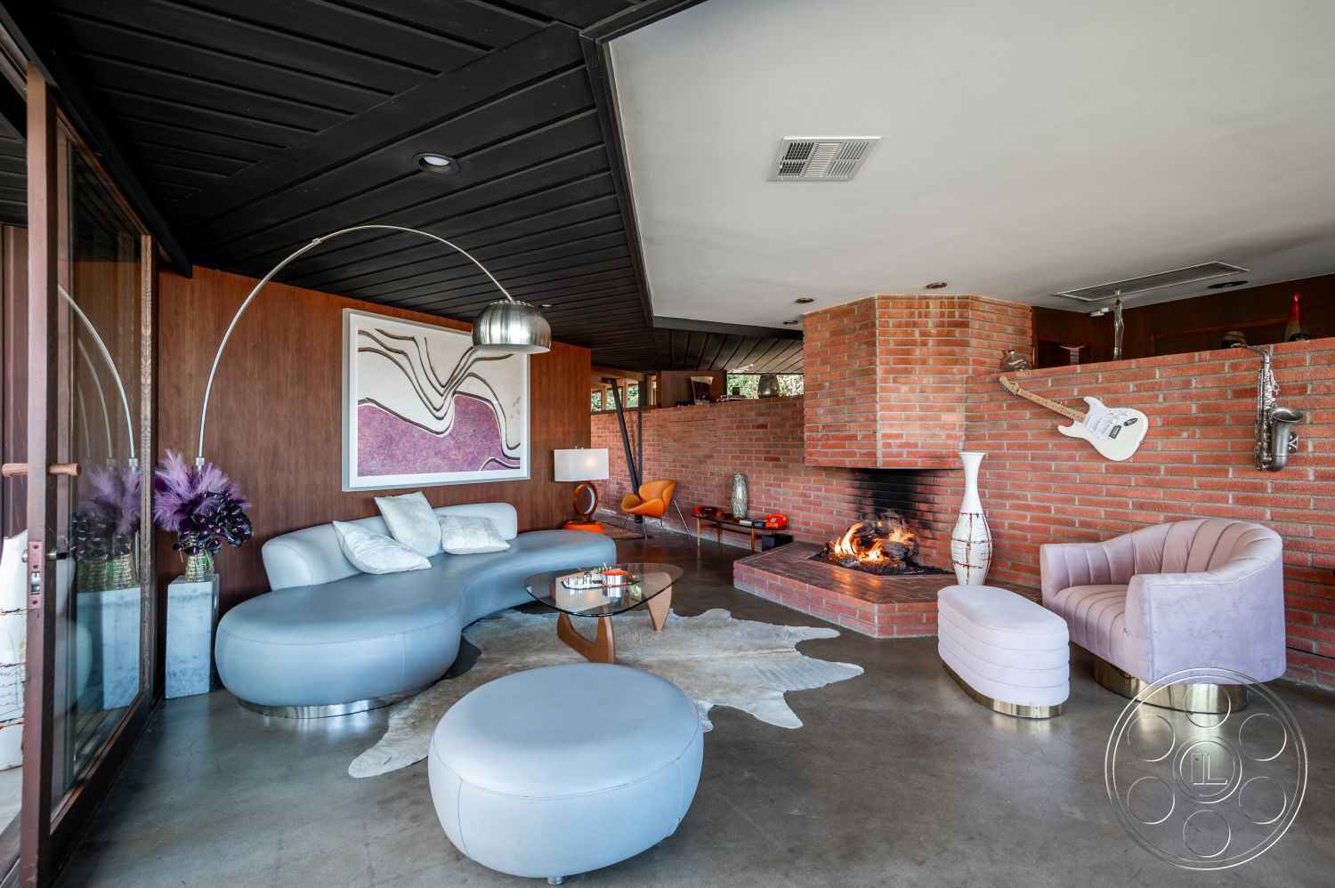 Retro 31 - neutral color palette, floor-to-ceiling windows, mid-century modern architectural style, exposed brick fireplace surround, natural light interior, open floor plan living area, curved modern sofa, concrete living room floor, abstract art wall decor, warm ambient lighting fixtures, plush velvet accent chairs, black wood paneling ceiling, metallic side tables, zebra patterned area rug, smooth marble side table, elegant white table lamps, rounded ottoman seating, cozy fireplace with integrated wood storage, modernist furniture design, interior living space with mixed materials