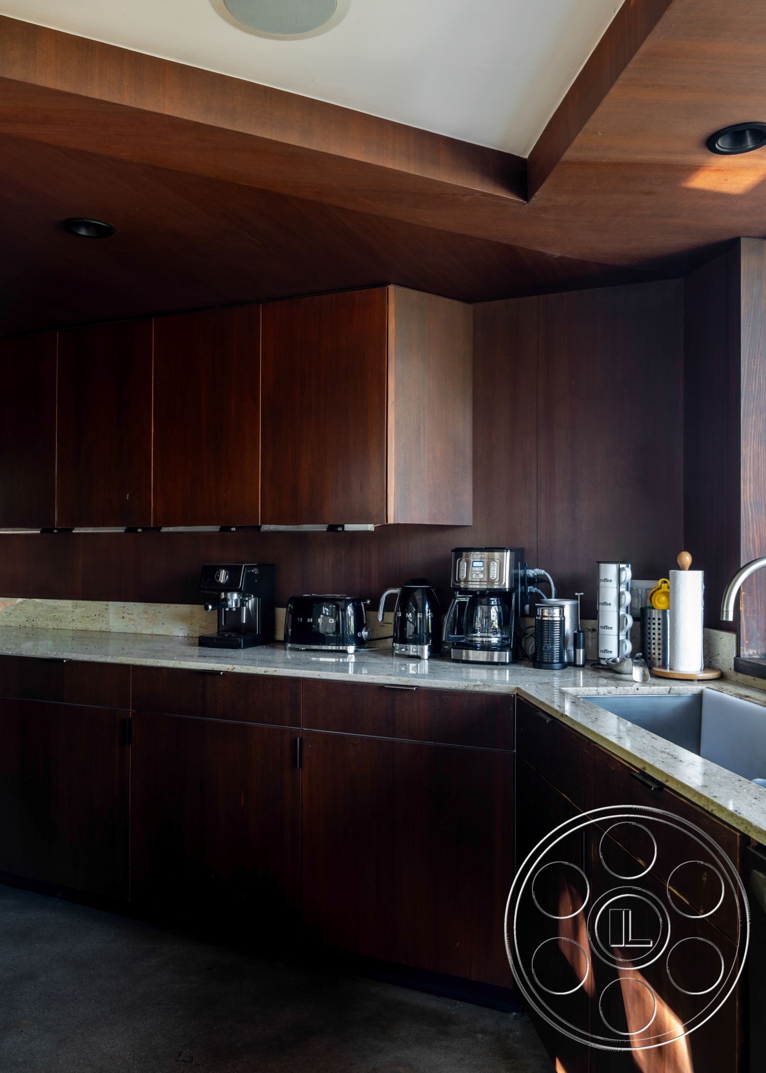 Retro 31 - dark wood cabinetry, smooth concrete flooring, granite countertops, stainless steel sink, decorative kitchen accessories, interior kitchen space, open kitchen design, ambient recessed lighting, minimalist kitchen layout, coffee station area, textured ceiling design, modern appliance fixtures, functional countertop workspace, high-end kitchen hardware