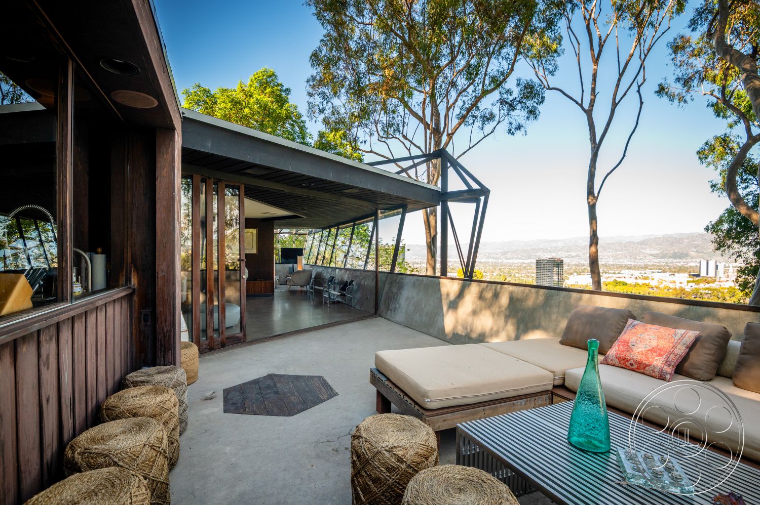 Retro 31 - natural light, exterior, stone accent wall, open concept layout, sliding glass doors, textured wall finish, floor-to-ceiling windows, modern architectural style, wooden privacy screen, circular seating area, urban hillside location, wood beam ceiling, concrete patio floor, minimalist outdoor furniture, landscape foliage, steel beam roof structure, mountain view patio setting