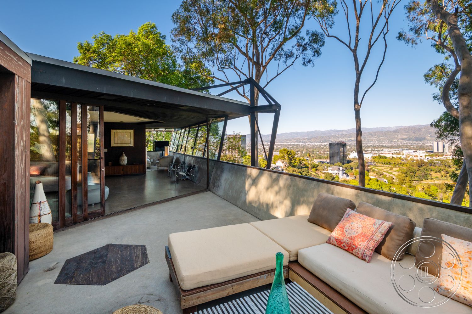 Retro 31 - exterior concrete patio floor, interior vaulted ceiling, interior dark wood paneling, interior decorative throw pillows, interior contemporary furniture, exterior floor-to-ceiling windows, exterior stone feature wall, exterior landscaped garden setting, exterior horizontal wood slats, exterior concrete wall, exterior lounge seating area, exterior city skyline view, exterior hillside location, interior modern lounge area, interior mid-century modern design, interior open-plan living space, interior artistic wall decor, exterior glass partition walls, exterior wooden beam ceiling, exterior wraparound deck