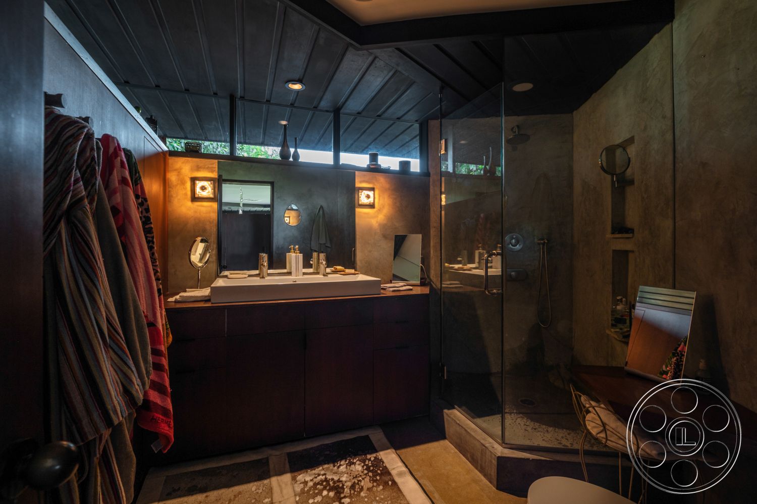 Retro 31 - glass shower enclosure, minimalist design elements, rectangular mirror, textured plaster walls, natural light from windows, dark wood paneling, exposed ceiling beams, metal light fixtures, interior bathroom, concrete sink countertop, modern faucet fixtures, wood vanity cabinet, modern wall art, warm lighting ambiance, compact workspace corner