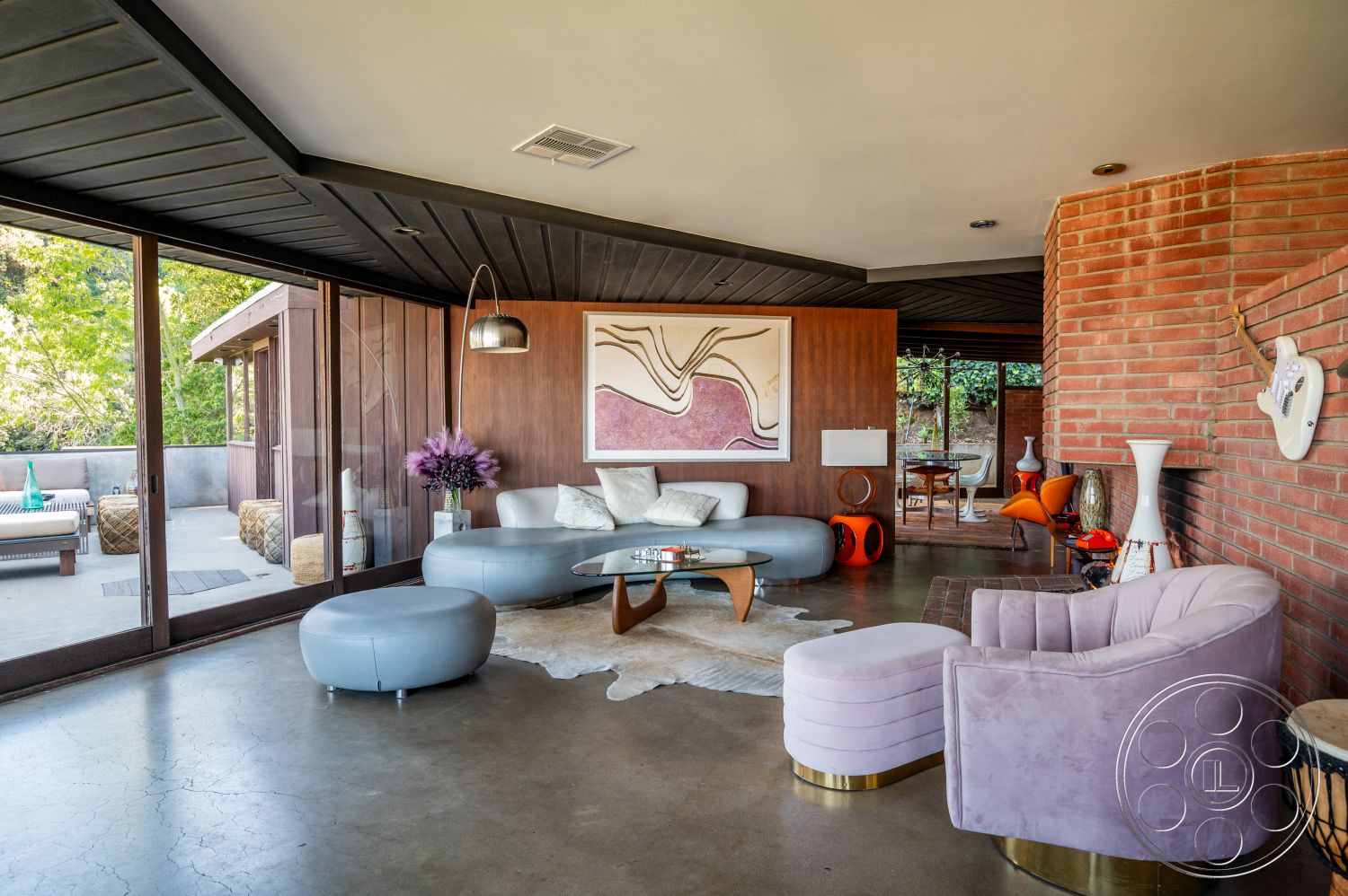 Retro 31 - minimalist decor, large glass sliding doors, textured area rug, open floor plan, decorative vases, concrete floor, spacious living area, contemporary design elements, outdoor patio view, natural light flooding in, exposed brick accent wall, modern lounge seating, wood paneling details, vaulted ceiling with black wood beams, curved coffee table, artwork feature wall, stylish purple accent chair, organically shaped furniture