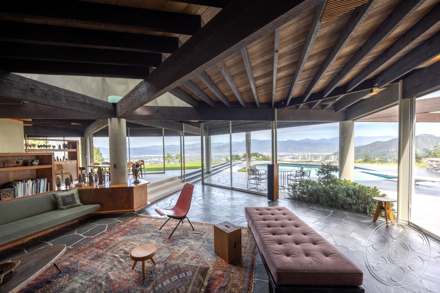 Retro 19 - exposed wood ceiling beams interior, natural light-filled space interior, landscaped garden view exterior, wooden accent wall interior, slate flooring living room, open concept floor plan interior, large glass wall with mountain view exterior, built-in wooden shelves interior, modern coffee table living room interior, low-profile sectional sofa interior, textured rugs living area interior, rectangular swimming pool exterior, curved patio area exterior, contemporary dining area interior, ranch-style home with outdoor living spaces exterior