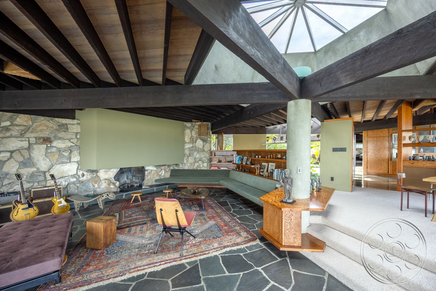 Retro 19 - natural light, round coffee table, minimalist aesthetic, contemporary furniture, floor-to-ceiling windows, natural stone flooring, stone feature wall, textured beige walls, mid-century modern architecture, glass skylight, warm wood accents, exposed wood ceiling beams, interior living space, open-concept living area, modern interior design, integrated lighting fixtures, lounge seating area, custom wood cabinetry, area rug accent, outdoor landscape view