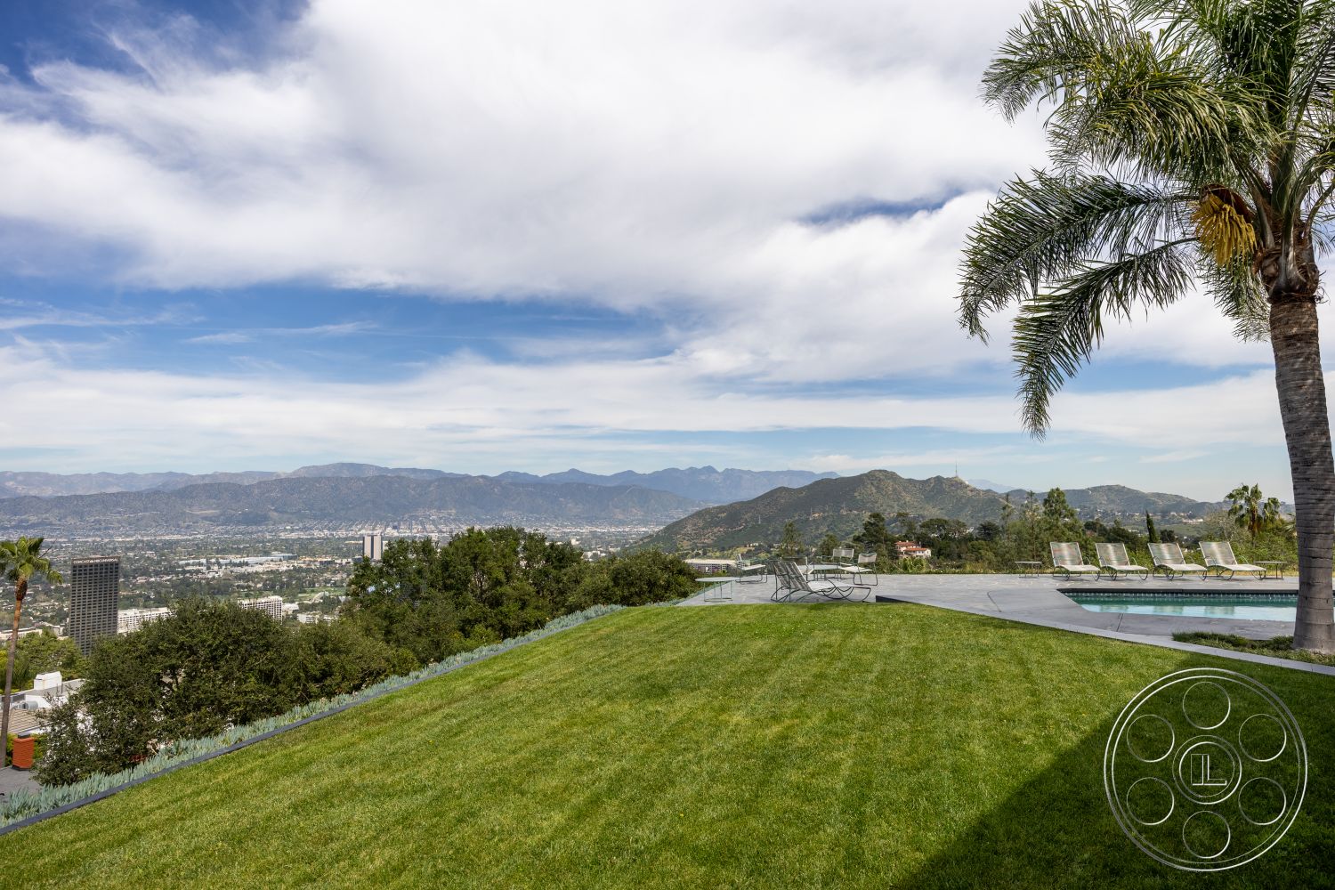 Retro 19 - exterior, modern architecture, palm trees, lush green lawn, landscaped hillside, mountain view, city skyline, outdoor lounge chairs, concrete pool deck, contemporary outdoor space, scenic backdrop, open sky, expansive patio area, sloped yard, luxury pool area, sunny weather