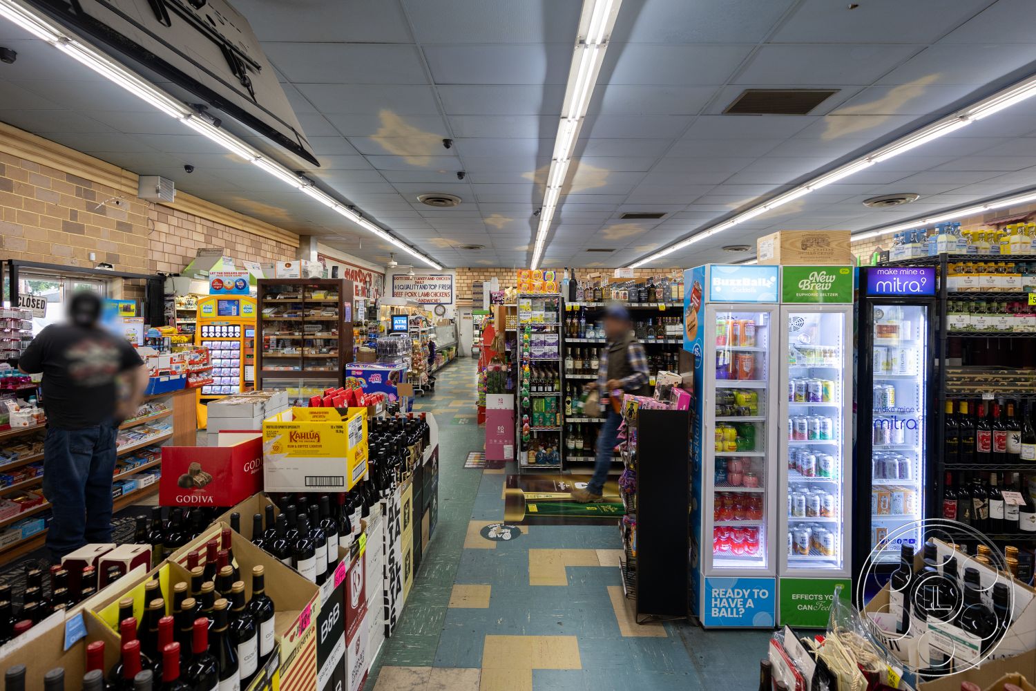 Shop 128 - open floor space, suspended ceiling tiles, fluorescent ceiling lights, brick accent walls, refrigerated display cases, retail store layout, commercial vinyl flooring, shelving units for beverages, product packaging displays, varied wine bottle arrangements, cardboard product boxes, merchandise checkout counter, aisles for customer navigation, store signage