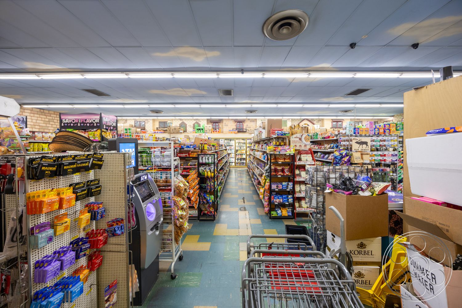 Shop 128 - fluorescent lighting, metal shelving units, exposed brick accent wall, vinyl composite tile flooring, aisle layout, striped ceiling tiles, point-of-sale counter, shopping cart display, variety of consumer goods, packaged foods, beverage refrigerators, snack shelving, commercial grocery store design